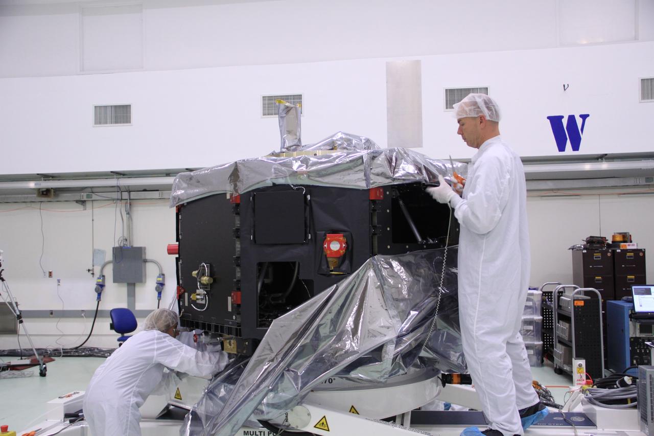 CAPE CANAVERAL, Fla. – In the clean room high bay at the Astrotech payload processing facility near NASA’s Kennedy Space Center in Florida, Applied Physics Laboratory technicians remove the protective shroud from around NASA's Radiation Belt Storm Probe B. Prelaunch preparations and spacecraft testing will follow.      The Radiation Belt Storm Probes, or RBSP, mission will help us understand the sun’s influence on Earth and near-Earth space by studying the Earth’s radiation belts on various scales of space and time. RBSP instruments will provide the measurements needed to characterize and quantify the plasma processes that produce very energetic ions and relativistic electrons. The mission is part of NASA’s broader Living With a Star Program that was conceived to explore fundamental processes that operate throughout the solar system, particularly those that generate hazardous space weather effects in the vicinity of Earth and phenomena that could impact solar system exploration. RBSP will begin its mission of exploration of Earth's Van Allen radiation belts and the extremes of space weather after launch. Launch aboard a United Launch Alliance Atlas V rocket is scheduled for August 23. For more information, visit http://www.nasa.gov/rbsp. Photo credit: NASA/Jim Grossmann