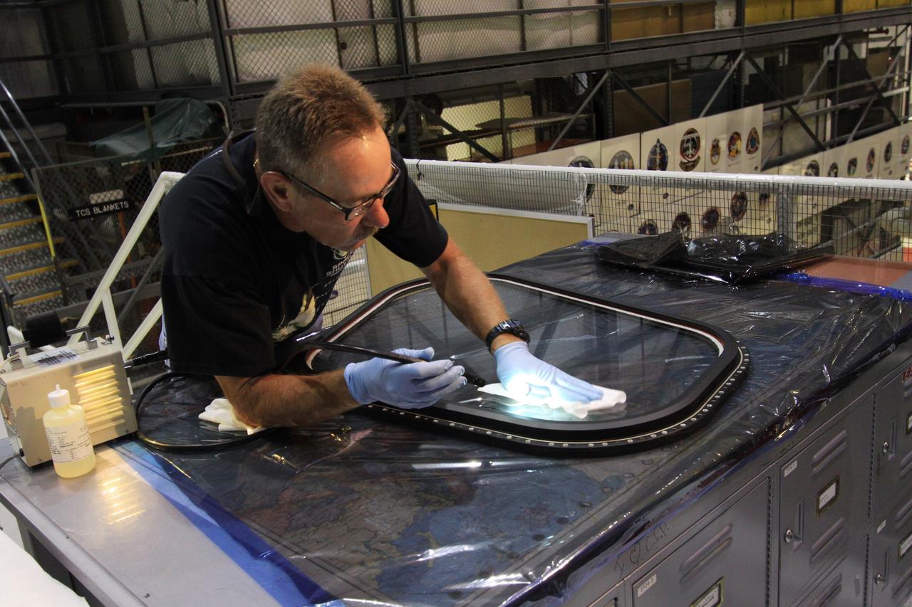 CAPE CANAVERAL, Fla. – Inside Orbiter Processing Facility-1 at NASA’s Kennedy Space Center in Florida, a United Space Alliance technician inspects window No. 4 for imperfections before it is installed on space shuttle Atlantis.     The work is part of the Space Shuttle Program’s transition and retirement processing of space shuttles Atlantis and Endeavour. Atlantis is being prepared for display at the Kennedy Space Center Visitor Complex and is scheduled to roll over to the complex in November. The visitor complex is targeting a July 2013 grand opening for Atlantis’ new home. Photo credit: NASA/Jim Grossmann