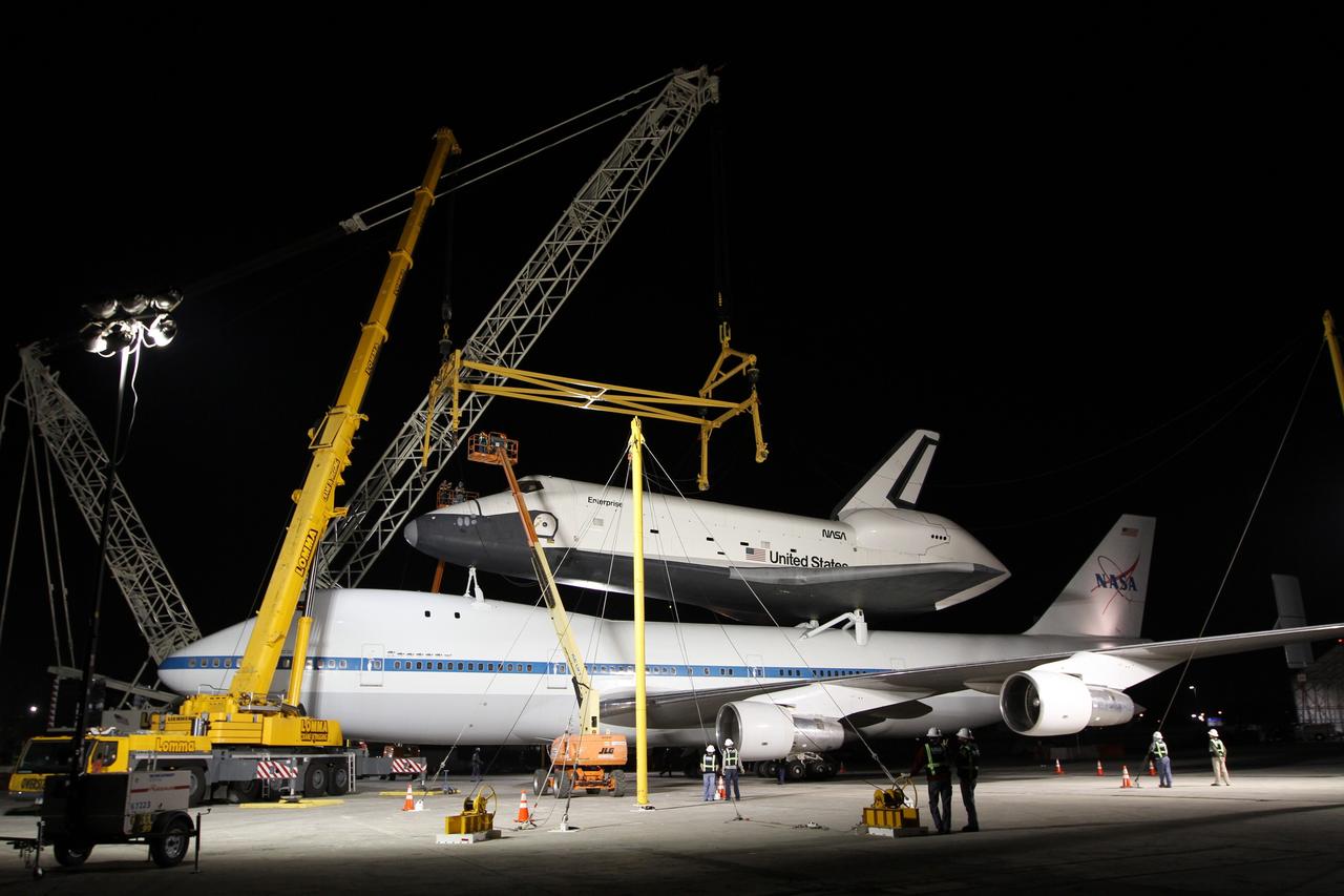 NEW YORK – A metal sling designed for lifting a space shuttle is positioned over space shuttle Enterprise and NASA's shuttle carrier aircraft. The work took place at John F. Kennedy International Airport in New York City. Enterprise, a prototype built to test aspects of the space shuttle design, will be displayed at the Intrepid Sea, Air and Space Museum in New York. Photo credit: NASA/Kim Shiflett