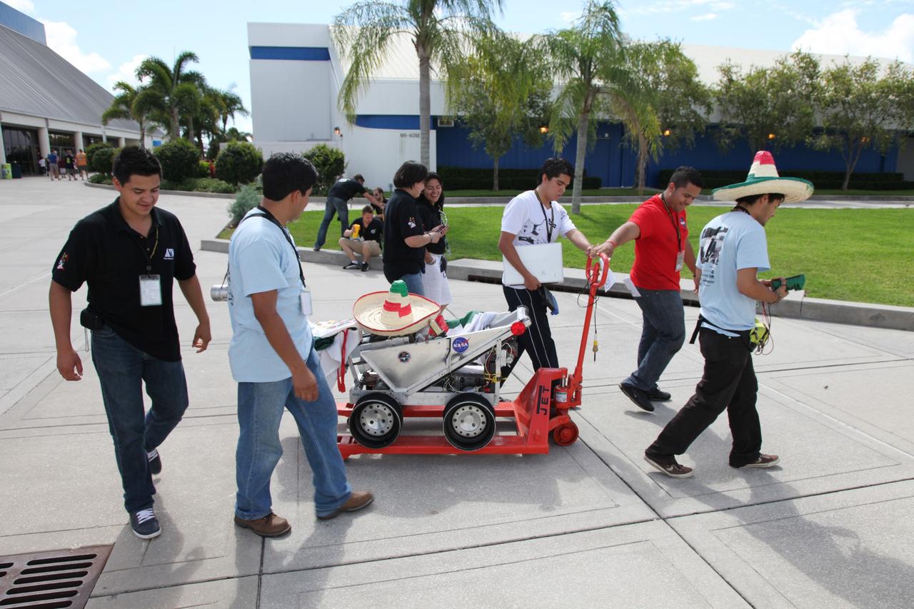 CAPE CANAVERAL, Fla. – At NASA’s Kennedy Space Center Visitor Complex in Florida, Lunabotics UAM Team students from the Universidad Autonoma Metropolitano in Mexico transport their lunabot to the Lunarena during NASA’s Lunabotics Mining Competition.    The mining competition is sponsored by NASA Kennedy Space Center’s Education Office for the agency’s Exploration Systems Mission Directorate. Undergraduate and graduate students from more than 50 universities and colleges in the U.S. and other countries use their remote-controlled Lunabots to maneuver and dig in a supersized sandbox filled with a crushed material that has characteristics similar to lunar soil. For more information, visit www.nasa.gov/lunabotics. Photo credit: NASA/Frankie Martin