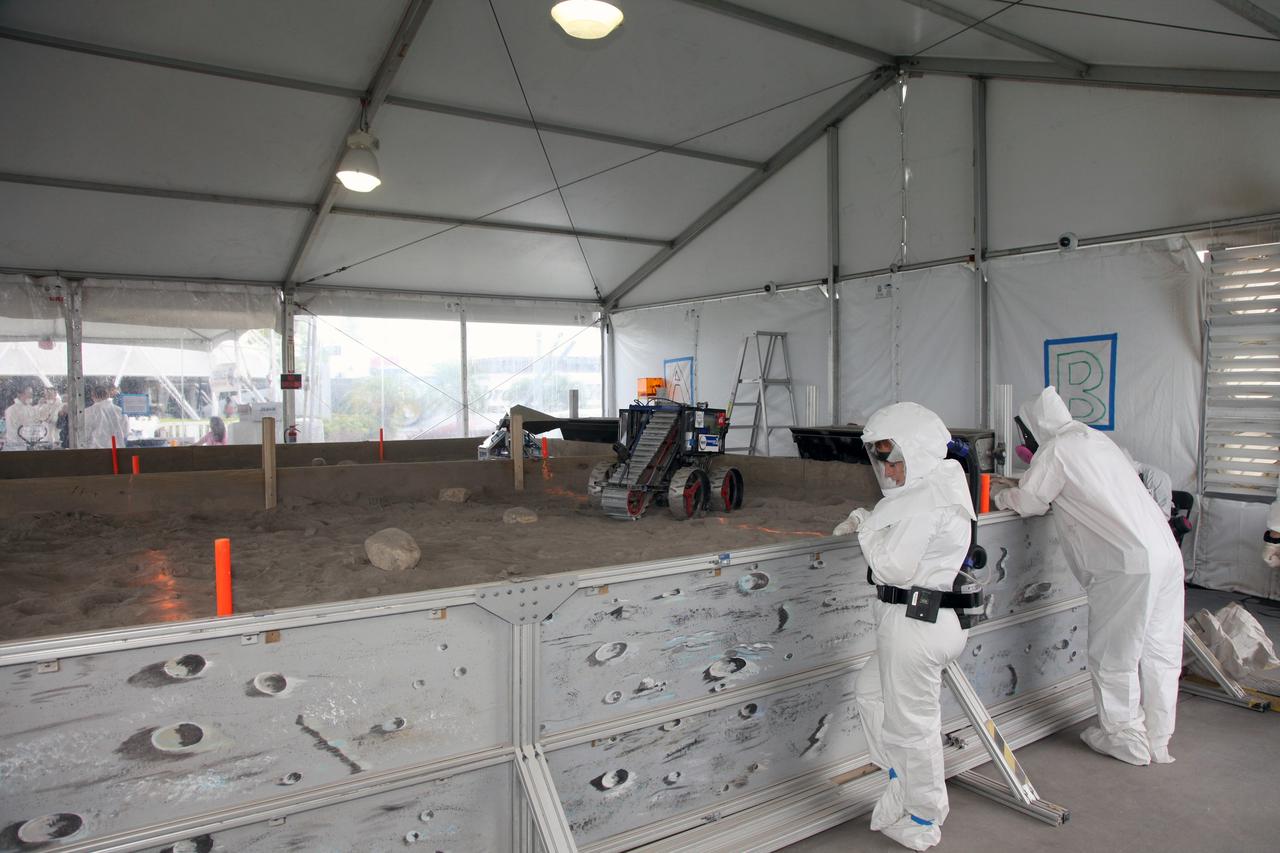 CAPE CANAVERAL, Fla. – At NASA’s Kennedy Space Center Visitor Complex in Florida, two judges monitor the progress of two Lunabots inside the Lunarena during NASA’s Lunabotics Mining Competition.    The mining competition is sponsored by NASA Kennedy Space Center’s Education Office for the agency’s Exploration Systems Mission Directorate. Undergraduate and graduate students from more than 50 universities and colleges in the U.S. and other countries use their remote-controlled Lunabots to maneuver and dig in a supersized sandbox filled with a crushed material that has characteristics similar to lunar soil. For more information, visit www.nasa.gov/lunabotics. Photo credit: NASA/Frankie Martin