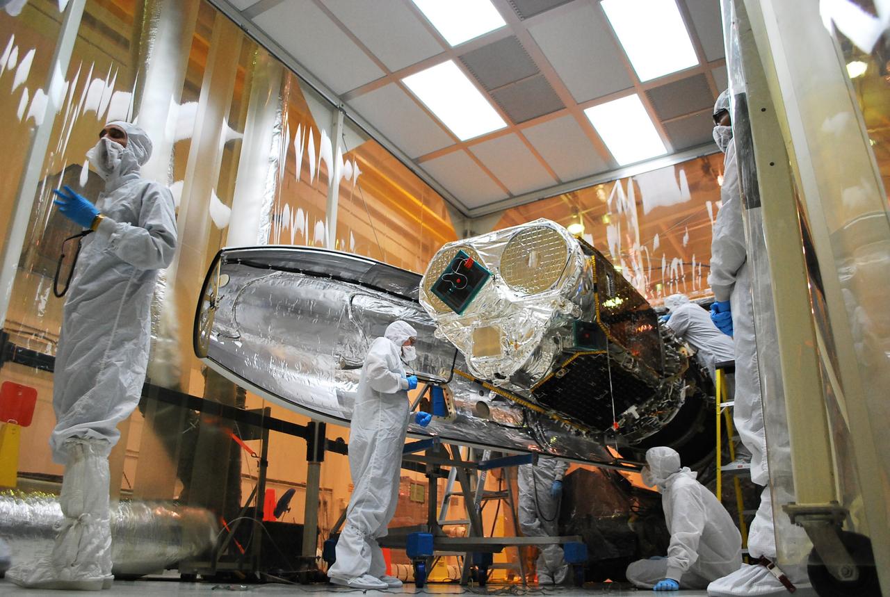 VANDENBERG AFB, Calif. – Technicians install one half of the payload fairing over the NuSTAR spacecraft as they continue to process the spacecraft and its Pegasus rocket for launch. NuSTAR stands for Nuclear Spectroscopic Telescope Array. Photo credit: NASA/Randy Beaudoin
