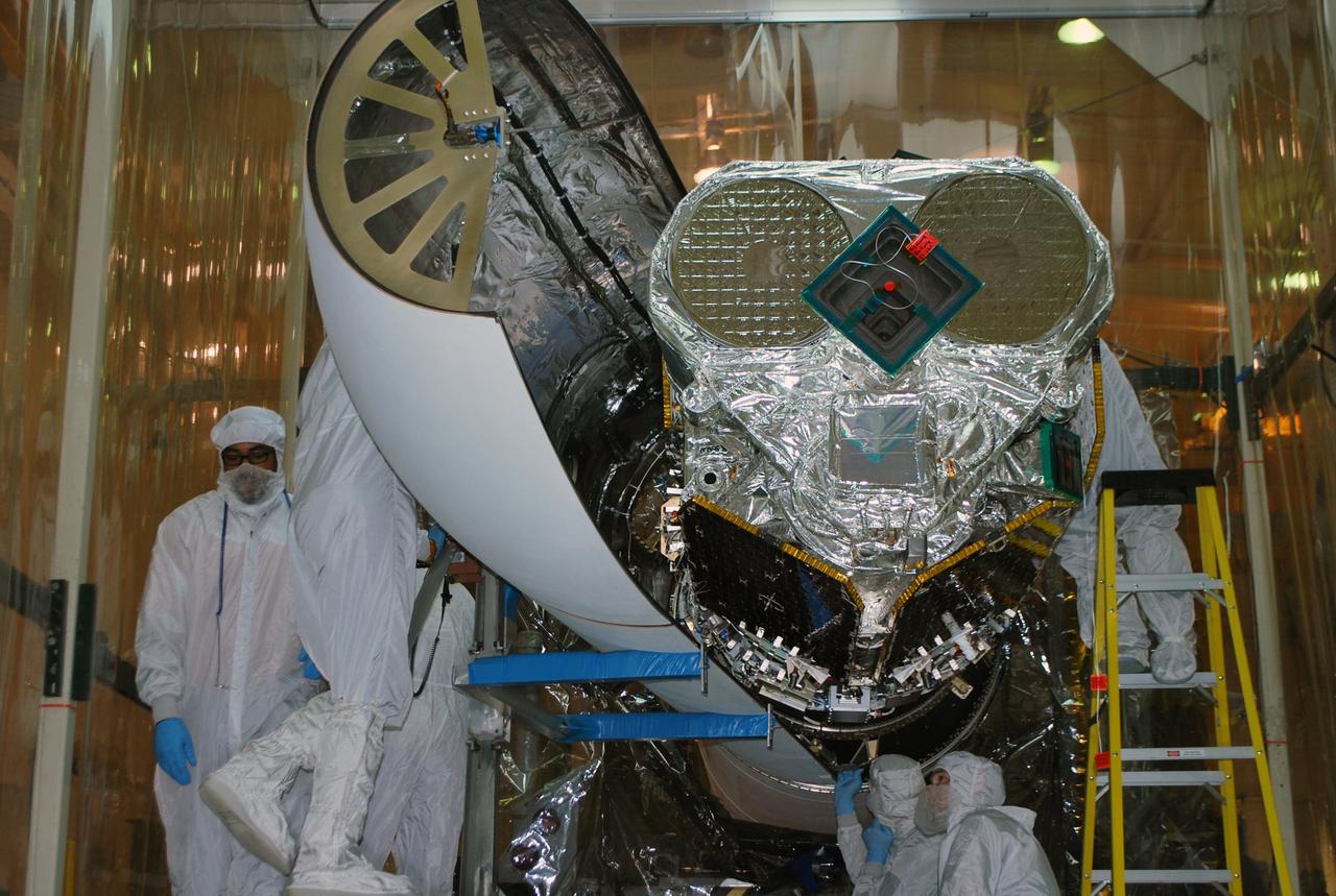 VANDENBERG AFB, Calif. – Technicians install one half of the payload fairing over the NuSTAR spacecraft as they continue to process the spacecraft and its Pegasus rocket for launch. NuSTAR stands for Nuclear Spectroscopic Telescope Array. Photo credit: NASA/Randy Beaudoin