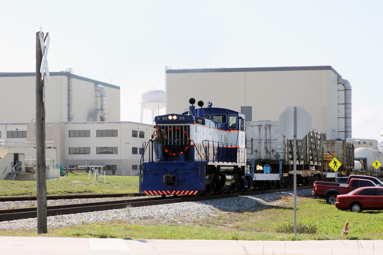 CAPE CANAVERAL, Fla. – A NASA Railroad train passes in front of the twin bays of the Orbiter Processing Facility at NASA’s Kennedy Space Center in Florida.  The train is on its way to the Florida East Coast Railway interchange in Titusville, Fla., where the train’s helium tank cars, a liquid oxygen tank car, and a liquid hydrogen dewar or tank car will be transferred for delivery to the SpaceX engine test complex outside McGregor, Texas.    The railroad cars were needed in support of the Space Shuttle Program but currently are not in use by NASA following the completion of the program in 2011. Originally, the tankers belonged to the U.S. Bureau of Mines.  At the peak of the shuttle program, there were approximately 30 cars in the fleet.  About half the cars were returned to the bureau as launch activity diminished. Five tank cars are being loaned to SpaceX and repurposed to support their engine tests in Texas. Eight cars previously were shipped to California on loan to support the SpaceX Falcon 9 rocket launches from Space Launch Complex-4 on Vandenberg Air Force Base.  SpaceX already has three helium tank cars previously used for the shuttle program at Space Launch Complex-40 on Cape Canaveral Air Force Station in Florida. For more information, visit http://www.nasa.gov/spacex.  Photo credit: NASA/Jim Grossmann