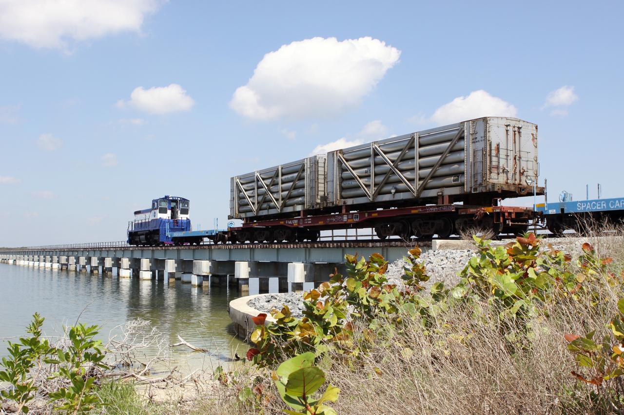 CAPE CANAVERAL, Fla. – A NASA Railroad train crosses the railroad’s Jay Jay Railroad Bridge north of Launch Complex 39 at NASA’s Kennedy Space Center in Florida. The train is on its way to the Florida East Coast Railway interchange in Titusville, Fla., where the train’s helium tank cars, a liquid oxygen tank car, and a liquid hydrogen dewar or tank car will be transferred for delivery to the SpaceX engine test complex outside McGregor, Texas.    The railroad cars were needed in support of the Space Shuttle Program but currently are not in use by NASA following the completion of the program in 2011. Originally, the tankers belonged to the U.S. Bureau of Mines.  At the peak of the shuttle program, there were approximately 30 cars in the fleet.  About half the cars were returned to the bureau as launch activity diminished. Five tank cars are being loaned to SpaceX and repurposed to support their engine tests in Texas. Eight cars previously were shipped to California on loan to support the SpaceX Falcon 9 rocket launches from Space Launch Complex-4 on Vandenberg Air Force Base.  SpaceX already has three helium tank cars previously used for the shuttle program at Space Launch Complex-40 on Cape Canaveral Air Force Station in Florida. For more information, visit http://www.nasa.gov/spacex.  Photo credit: NASA/Jim Grossmann