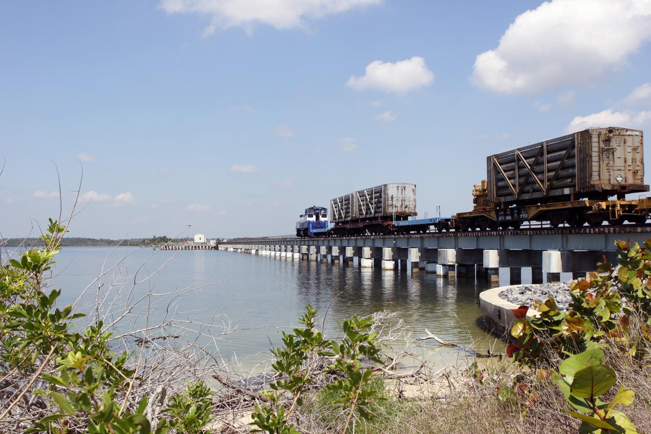 CAPE CANAVERAL, Fla. – A NASA Railroad train crosses the railroad’s Jay Jay Railroad Bridge north of Launch Complex 39 at NASA’s Kennedy Space Center in Florida. The train is on its way to the Florida East Coast Railway interchange in Titusville, Fla., where the train’s helium tank cars, a liquid oxygen tank car, and a liquid hydrogen dewar or tank car will be transferred for delivery to the SpaceX engine test complex outside McGregor, Texas.    The railroad cars were needed in support of the Space Shuttle Program but currently are not in use by NASA following the completion of the program in 2011. Originally, the tankers belonged to the U.S. Bureau of Mines.  At the peak of the shuttle program, there were approximately 30 cars in the fleet.  About half the cars were returned to the bureau as launch activity diminished. Five tank cars are being loaned to SpaceX and repurposed to support their engine tests in Texas. Eight cars previously were shipped to California on loan to support the SpaceX Falcon 9 rocket launches from Space Launch Complex-4 on Vandenberg Air Force Base.  SpaceX already has three helium tank cars previously used for the shuttle program at Space Launch Complex-40 on Cape Canaveral Air Force Station in Florida. For more information, visit http://www.nasa.gov/spacex.  Photo credit: NASA/Jim Grossmann