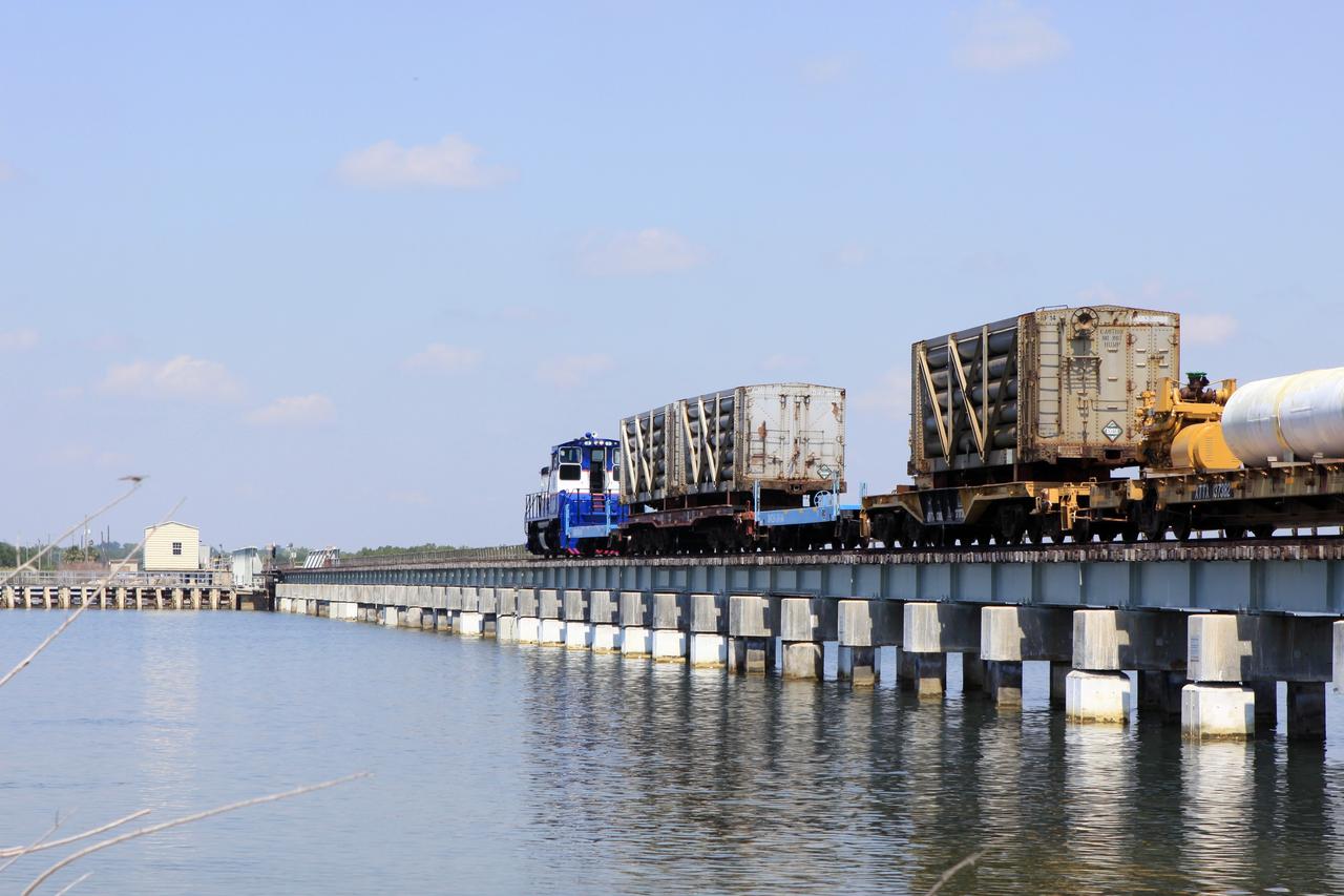 CAPE CANAVERAL, Fla. – A NASA Railroad train crosses the railroad’s Jay Jay Railroad Bridge north of Launch Complex 39 at NASA’s Kennedy Space Center in Florida. The train is on its way to the Florida East Coast Railway interchange in Titusville, Fla., where the train’s helium tank cars, a liquid oxygen tank car, and a liquid hydrogen dewar or tank car will be transferred for delivery to the SpaceX engine test complex outside McGregor, Texas.    The railroad cars were needed in support of the Space Shuttle Program but currently are not in use by NASA following the completion of the program in 2011. Originally, the tankers belonged to the U.S. Bureau of Mines.  At the peak of the shuttle program, there were approximately 30 cars in the fleet.  About half the cars were returned to the bureau as launch activity diminished. Five tank cars are being loaned to SpaceX and repurposed to support their engine tests in Texas. Eight cars previously were shipped to California on loan to support the SpaceX Falcon 9 rocket launches from Space Launch Complex-4 on Vandenberg Air Force Base.  SpaceX already has three helium tank cars previously used for the shuttle program at Space Launch Complex-40 on Cape Canaveral Air Force Station in Florida. For more information, visit http://www.nasa.gov/spacex.  Photo credit: NASA/Jim Grossmann