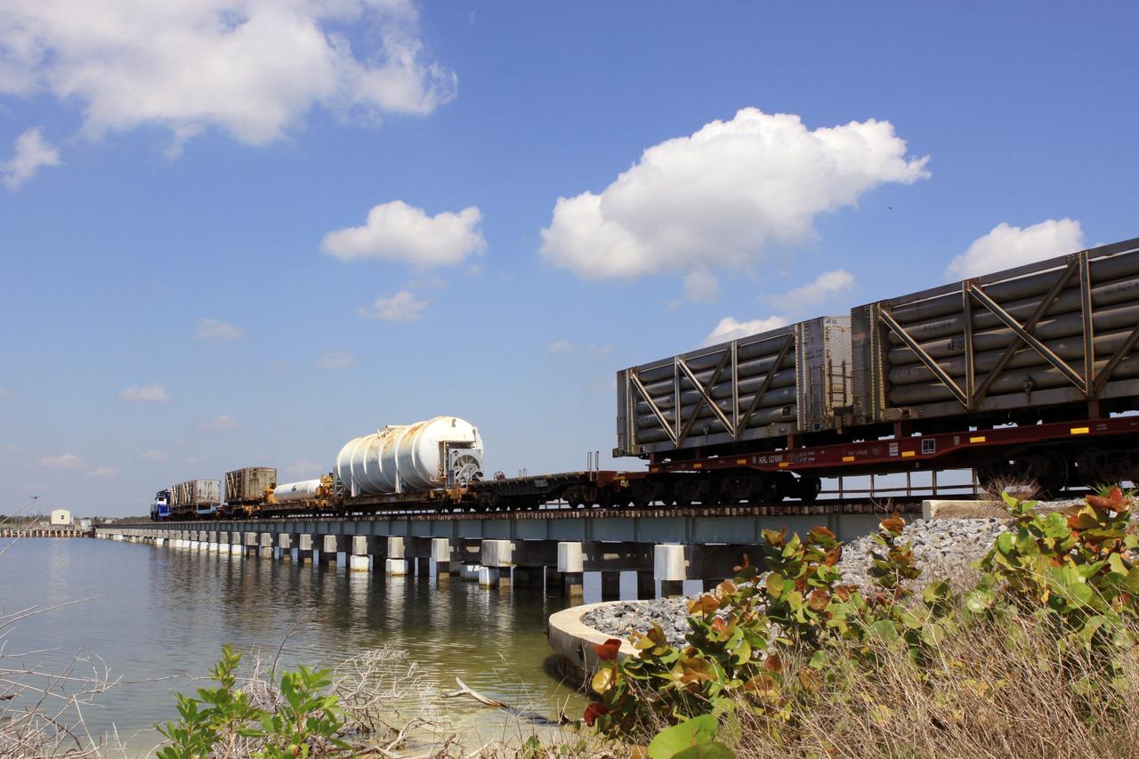 CAPE CANAVERAL, Fla. – A NASA Railroad train crosses the railroad’s Jay Jay Railroad Bridge north of Launch Complex 39 at NASA’s Kennedy Space Center in Florida. The train is on its way to the Florida East Coast Railway interchange in Titusville, Fla., where the train’s helium tank cars, a liquid oxygen tank car, and a liquid hydrogen dewar or tank car will be transferred for delivery to the SpaceX engine test complex outside McGregor, Texas. The helium tank cars are positioned in the front and rear of the train.  The long, thin tank car in the middle was used for liquid hydrogen, followed by a much larger tank car used for liquid oxygen.    The railroad cars were needed in support of the Space Shuttle Program but currently are not in use by NASA following the completion of the program in 2011. Originally, the tankers belonged to the U.S. Bureau of Mines.  At the peak of the shuttle program, there were approximately 30 cars in the fleet.  About half the cars were returned to the bureau as launch activity diminished. Five tank cars are being loaned to SpaceX and repurposed to support their engine tests in Texas. Eight cars previously were shipped to California on loan to support the SpaceX Falcon 9 rocket launches from Space Launch Complex-4 on Vandenberg Air Force Base.  SpaceX already has three helium tank cars previously used for the shuttle program at Space Launch Complex-40 on Cape Canaveral Air Force Station in Florida. For more information, visit http://www.nasa.gov/spacex.  Photo credit: NASA/Jim Grossmann