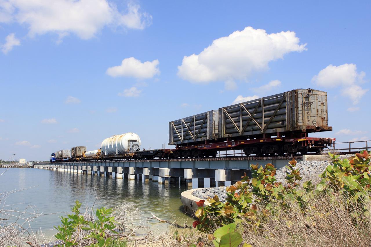 CAPE CANAVERAL, Fla. – A NASA Railroad train crosses the railroad’s Jay Jay Railroad Bridge north of Launch Complex 39 at NASA’s Kennedy Space Center in Florida. The train is on its way to the Florida East Coast Railway interchange in Titusville, Fla., where the train’s helium tank cars, a liquid oxygen tank car, and a liquid hydrogen dewar or tank car will be transferred for delivery to the SpaceX engine test complex outside McGregor, Texas. The helium tank cars are positioned in the front and rear of the train.  The long, thin tank car in the middle was used for liquid hydrogen, followed by a much larger tank car used for liquid oxygen.    The railroad cars were needed in support of the Space Shuttle Program but currently are not in use by NASA following the completion of the program in 2011. Originally, the tankers belonged to the U.S. Bureau of Mines.  At the peak of the shuttle program, there were approximately 30 cars in the fleet.  About half the cars were returned to the bureau as launch activity diminished. Five tank cars are being loaned to SpaceX and repurposed to support their engine tests in Texas. Eight cars previously were shipped to California on loan to support the SpaceX Falcon 9 rocket launches from Space Launch Complex-4 on Vandenberg Air Force Base.  SpaceX already has three helium tank cars previously used for the shuttle program at Space Launch Complex-40 on Cape Canaveral Air Force Station in Florida. For more information, visit http://www.nasa.gov/spacex.  Photo credit: NASA/Jim Grossmann