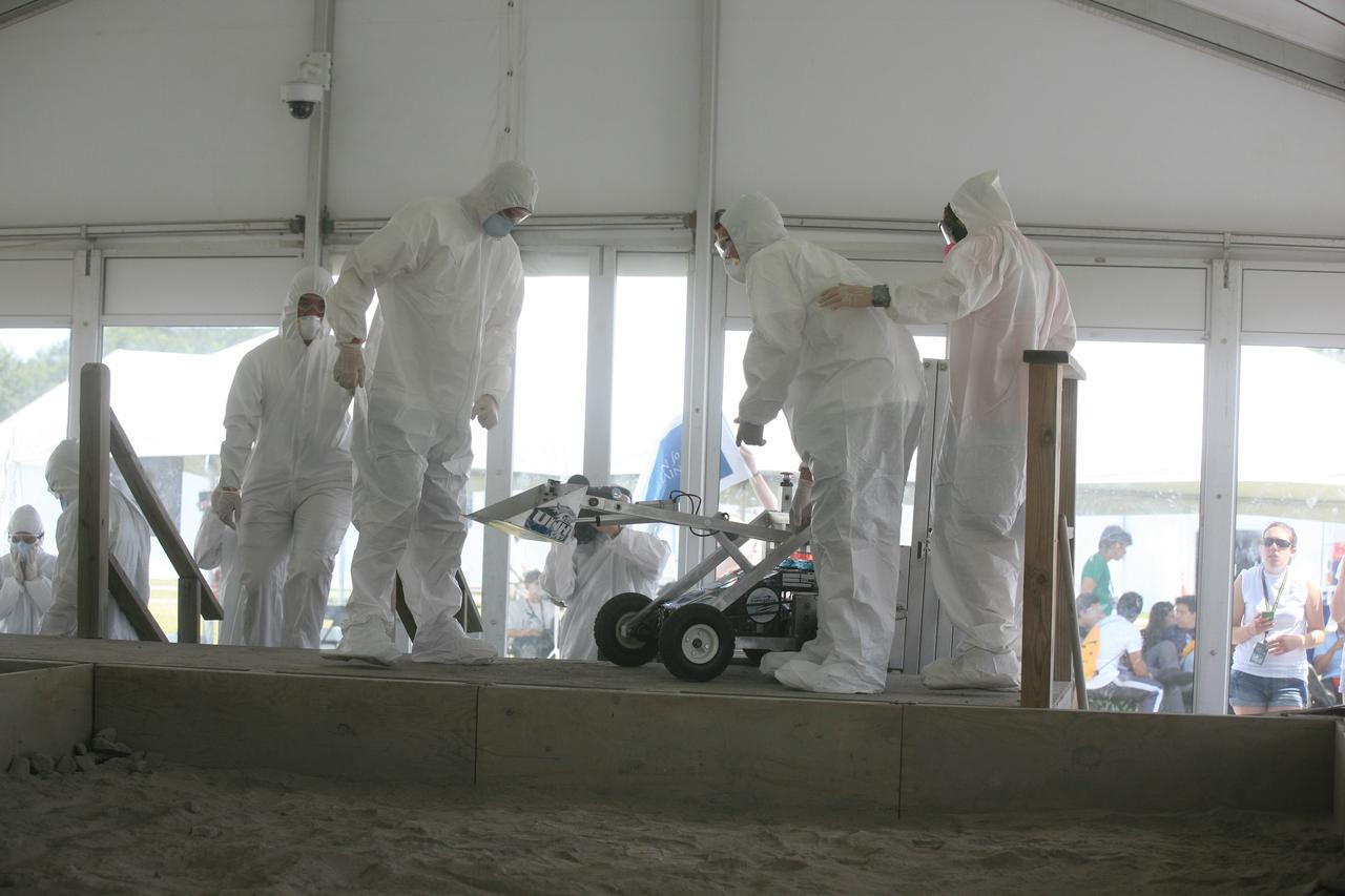 CAPE CANAVERAL, Fla. – A team of competitors works with a robotic vehicle taking part in NASA's Lunabotics Mining Competition at the Kennedy Space Center Visitor Complex in Florida. The competition challenges university students to build machines that can collect soil such as the material found on the moon. Working inside the Caterpillar LunArena, the robotic craft dig soil that simulates lunar material. The event is judged by a machine's abilities to collect the soil, its design and operation, size, dust tolerance and its level of autonomy. Photo credit: NASA/Glenn Benson