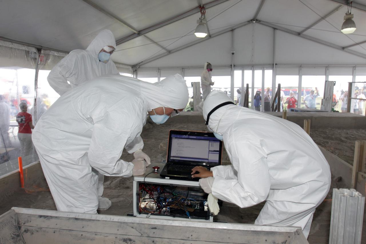 CAPE CANAVERAL, Fla. – A team of competitors works with its machine during NASA's Lunabotics Mining Competition at the Kennedy Space Center Visitor Complex in Florida. The competition challenges university students to build machines that can collect soil such as the material found on the moon. Working inside the Caterpillar LunArena, the robotic craft dig soil that simulates lunar material. The event is judged by a machine's abilities to collect the soil, its design and operation, size, dust tolerance and its level of autonomy. Photo credit: NASA/Glenn Benson