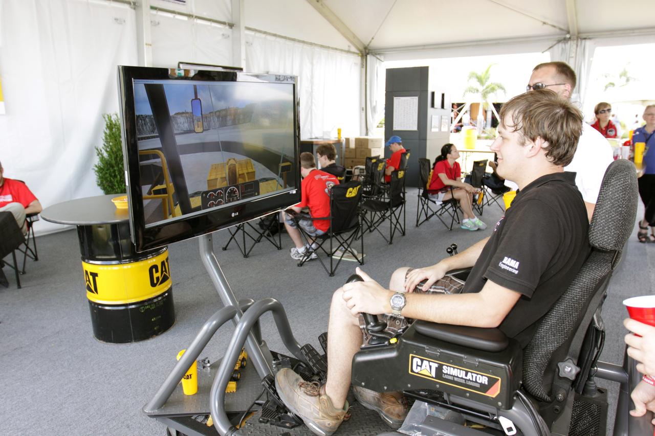 CAPE CANAVERAL, Fla. – A videogame simulates driving excavators during NASA's Lunabotics Mining Competition at the Kennedy Space Center Visitor Complex in Florida. The competition challenges university students to build machines that can collect soil such as the material found on the moon. Working inside the Caterpillar LunArena, the robotic craft dig soil that simulates lunar material. The event is judged by a machine's abilities to collect the soil, its design and operation, size, dust tolerance and its level of autonomy.  Photo credit: NASA/Glenn Benson