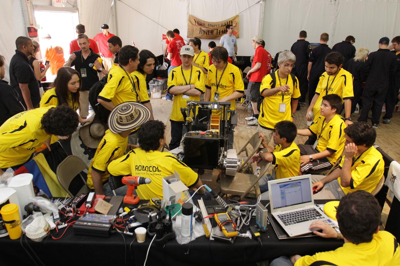 CAPE CANAVERAL, Fla. – A team of competitors works with its machine during NASA's Lunabotics Mining Competition at the Kennedy Space Center Visitor Complex in Florida. The competition challenges university students to build machines that can collect soil such as the material found on the moon. Working inside the Caterpillar LunArena, the robotic craft dig soil that simulates lunar material. The event is judged by a machine's abilities to collect the soil, its design and operation, size, dust tolerance and its level of autonomy. Photo credit: NASA/Glenn Benson