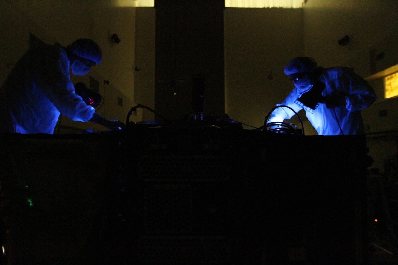 CAPE CANAVERAL, Fla. – Working in near-darkness inside the high bay clean room at the Astrotech payload processing facility, two technicians use black lights to inspect of one of NASA's twin Radiation Belt Storm Probes. Black light inspection uses UVA fluorescence to detect possible microcontamination, small cracks or fluid leaks.    The Radiation Belt Storm Probes, or RBSP, mission will help us understand the sun’s influence on Earth and near-Earth space by studying the Earth’s radiation belts on various scales of space and time. RBSP will begin its mission of exploration of Earth's Van Allen radiation belts and the extremes of space weather after its launch aboard a United Launch Alliance Atlas V rocket. For more information, visit http://www.nasa.gov/rbsp. Photo credit: NASA/Kim Shiflett