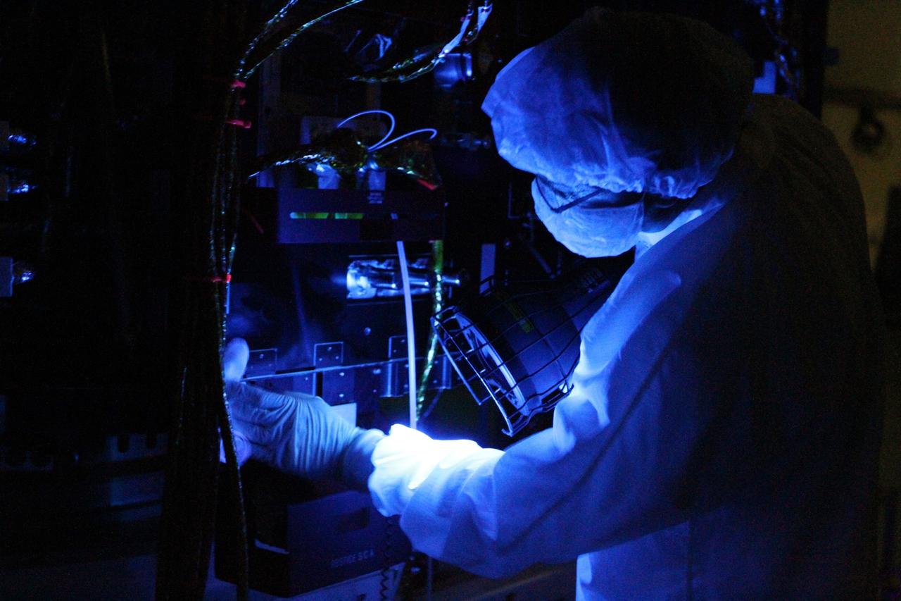 CAPE CANAVERAL, Fla. – Using a black light, a technician closely inspects one of NASA's twin Radiation Belt Storm Probes inside the clean room high bay at Astrotech payload processing facility. Black light inspection uses UVA fluorescence to detect possible microcontamination, small cracks or fluid leaks.    The Radiation Belt Storm Probes, or RBSP, mission will help us understand the sun’s influence on Earth and near-Earth space by studying the Earth’s radiation belts on various scales of space and time. RBSP will begin its mission of exploration of Earth's Van Allen radiation belts and the extremes of space weather after its launch aboard a United Launch Alliance Atlas V rocket. For more information, visit http://www.nasa.gov/rbsp. Photo credit: NASA/Kim Shiflett