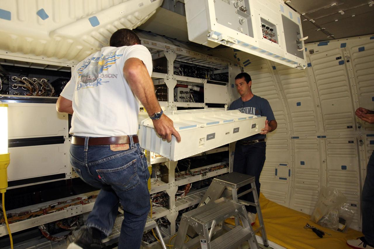 Technicians install lockers on the middeck of space shuttle Atlantis as the spacecraft is prepared for public display. The work is taking place as Atlantis sits inside Orbiter Processing Facility-1 at NASA's Kennedy Space Center in Florida. Photo credit: NASA/Dmitri Gerondidakis