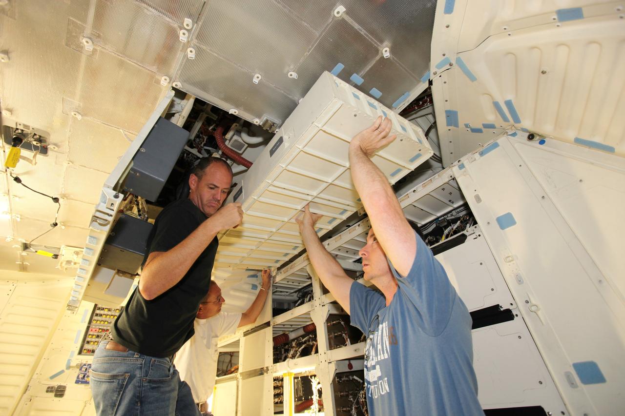 Technicians install lockers on the middeck of space shuttle Atlantis as the spacecraft is prepared for public display. The work is taking place as Atlantis sits inside Orbiter Processing Facility-1 at NASA's Kennedy Space Center in Florida. Photo credit: NASA/Dmitri Gerondidakis