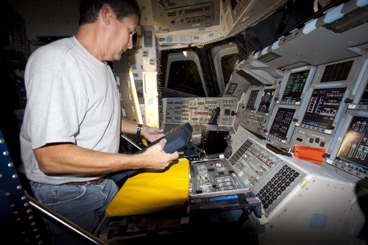 A technician outfits the commander and pilot seats on the flight deck of space shuttle Atlantis as the spacecraft is prepared for public display. The work is taking place as Atlantis sits inside Orbiter Processing Facility-1 at NASA's Kennedy Space Center in Florida. Photo credit: NASA/Dmitri Gerondidakis