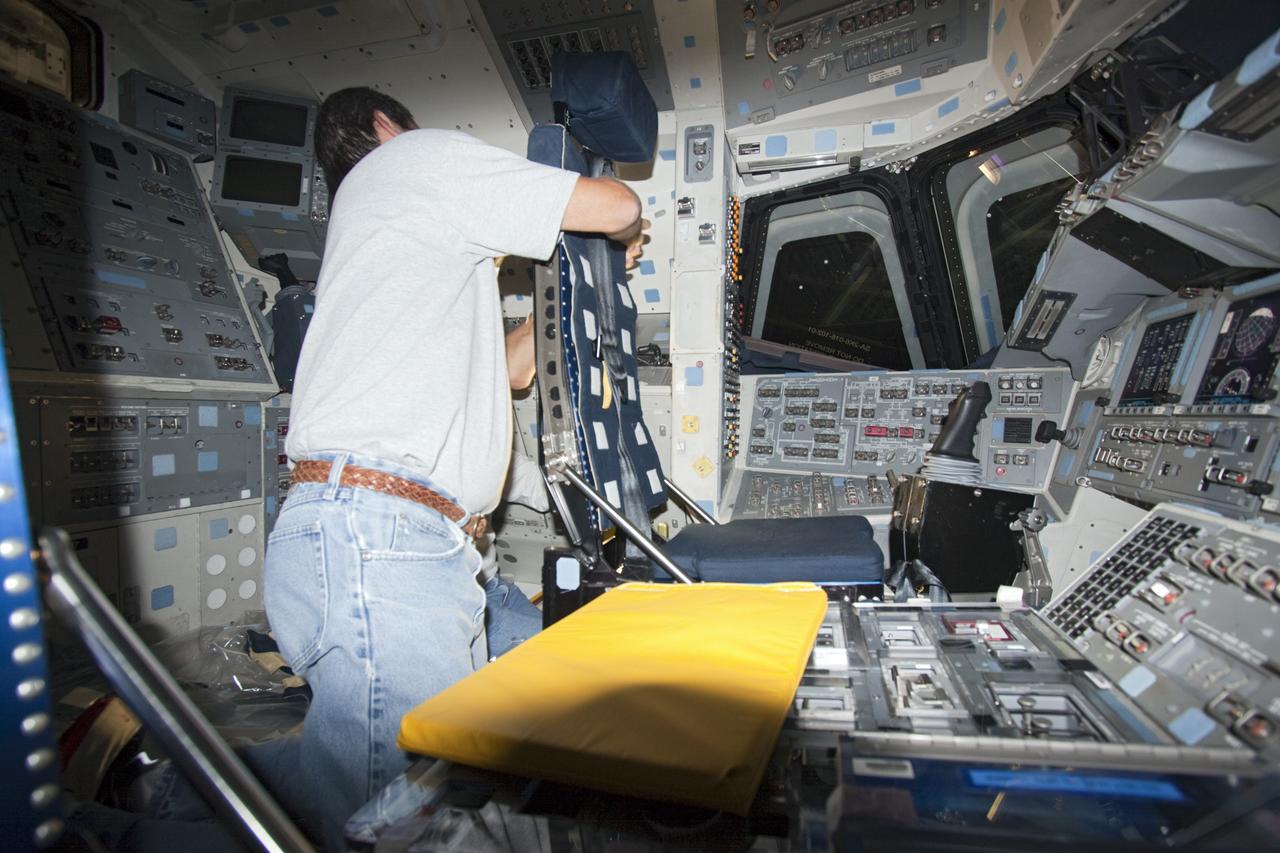 A technician outfits the commander and pilot seats on the flight deck of space shuttle Atlantis as the spacecraft is prepared for public display. The work is taking place as Atlantis sits inside Orbiter Processing Facility-1 at NASA's Kennedy Space Center in Florida. Photo credit: NASA/Dmitri Gerondidakis