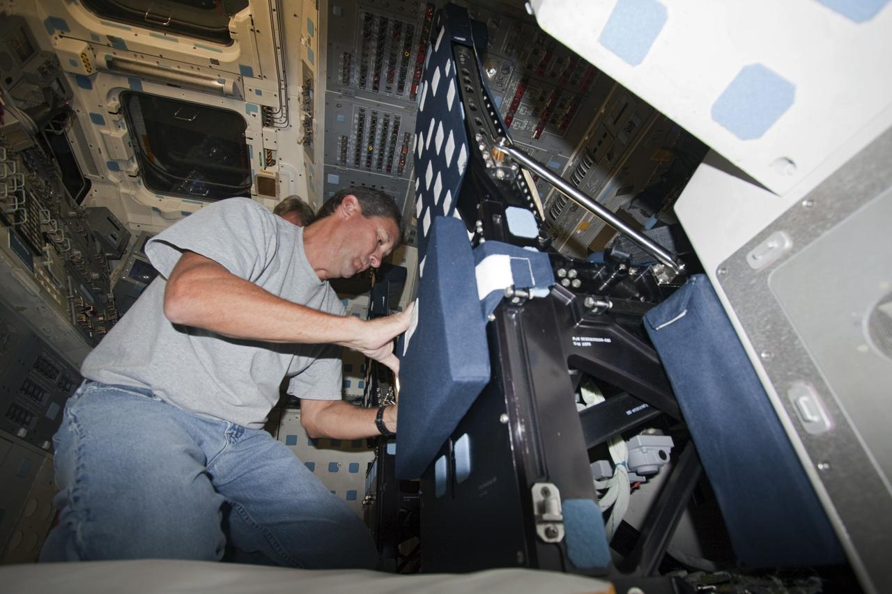 A technician outfits the commander and pilot seats on the flight deck of space shuttle Atlantis as the spacecraft is prepared for public display. The work is taking place as Atlantis sits inside Orbiter Processing Facility-1 at NASA's Kennedy Space Center in Florida. Photo credit: NASA/Dmitri Gerondidakis