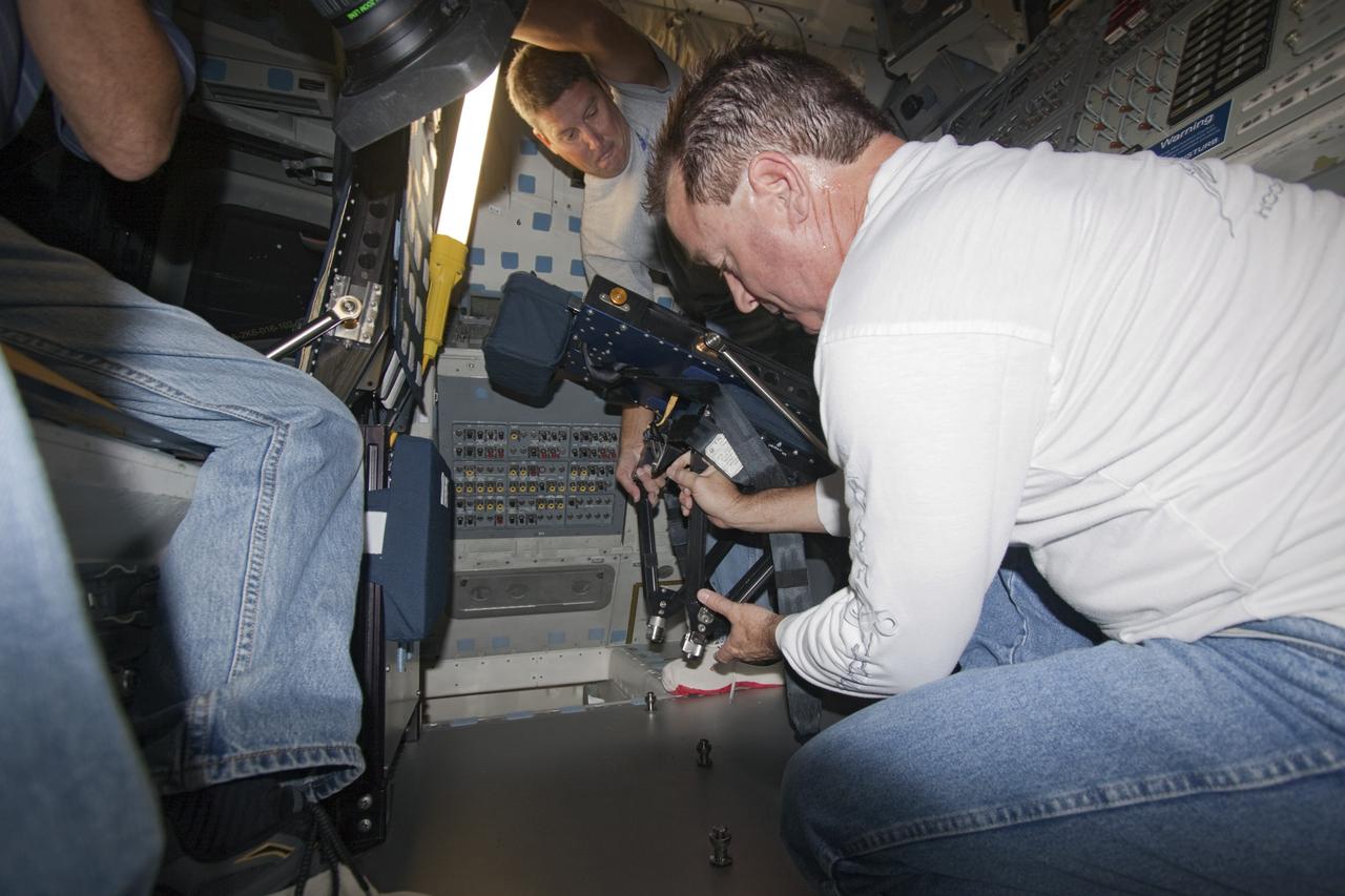Technicians move mission specialist seat into place inside space shuttle Atlantis as the spacecraft is prepared for public display. The work is taking place as Atlantis sits inside Orbiter Processing Facility-1 at NASA's Kennedy Space Center in Florida. Photo credit: NASA/Dmitri Gerondidakis