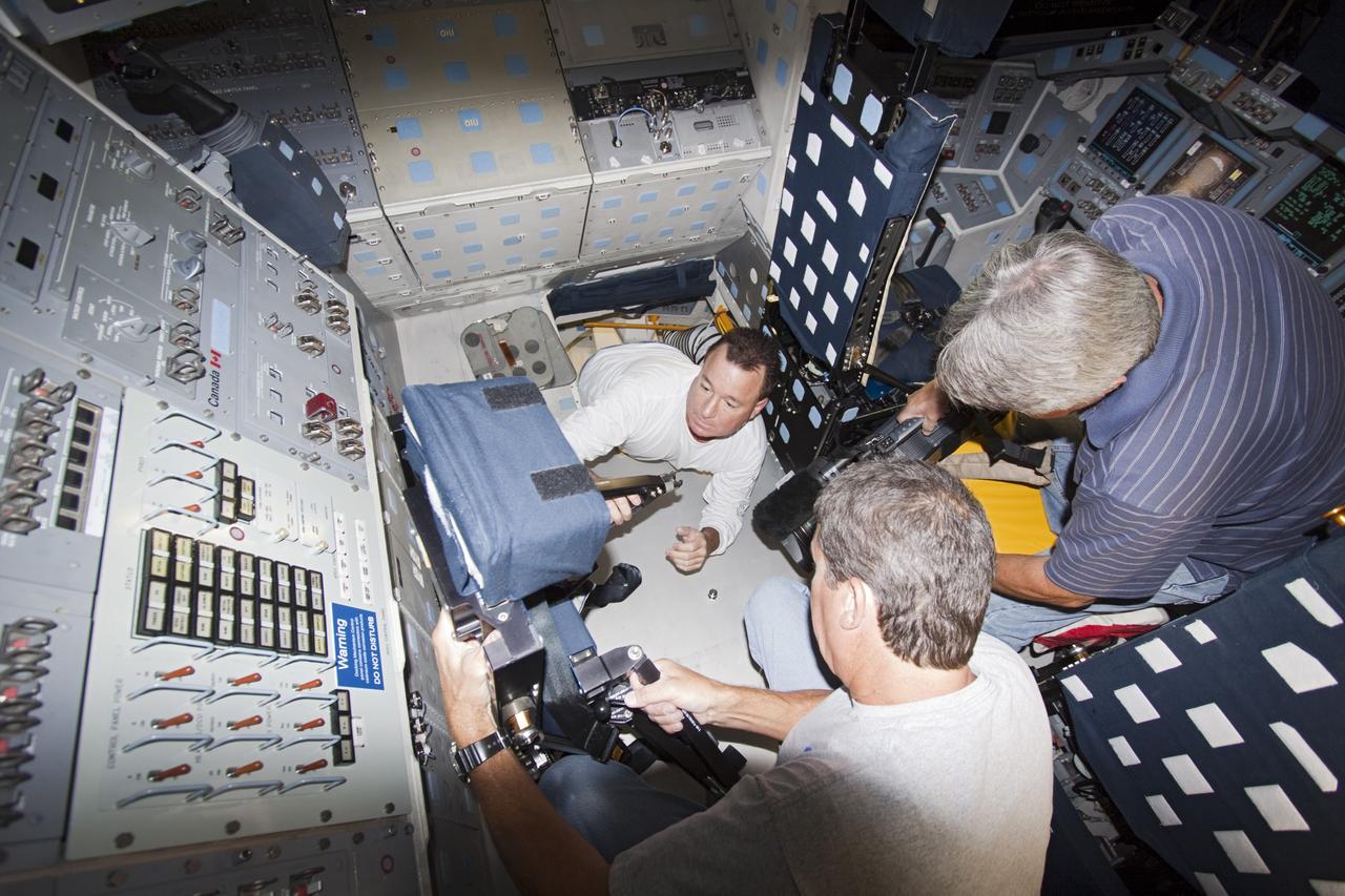 Technicians move mission specialist seat into place inside space shuttle Atlantis as the spacecraft is prepared for public display. The work is taking place as Atlantis sits inside Orbiter Processing Facility-1 at NASA's Kennedy Space Center in Florida. Photo credit: NASA/Dmitri Gerondidakis