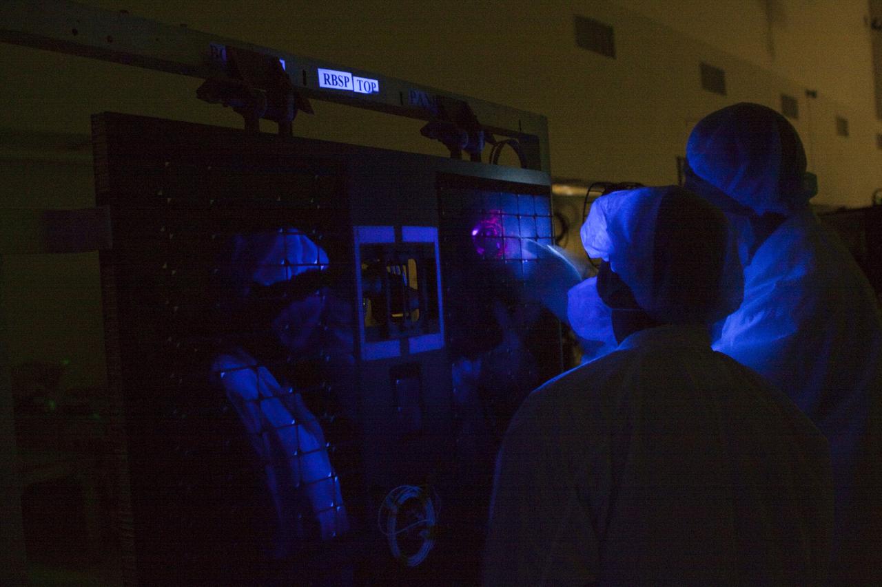 CAPE CANAVERAL, Fla. – Using a black light, technicians closely inspect a solar panel on one of NASA's twin Radiation Belt Storm Probes inside the clean room high bay at the Astrotech payload processing facility near NASA’s Kennedy Space Center in Florida.  The technicians are dressed in clean-room attire known as “bunny suits.”    Black-light inspection uses UVA fluorescence to detect possible microcontamination, small cracks or fluid leaks. The Radiation Belt Storm Probes, or RBSP, mission will help us understand the sun’s influence on Earth and near-Earth space by studying the Earth’s radiation belts on various scales of space and time. RBSP will begin its mission of exploration of Earth's Van Allen radiation belts and the extremes of space weather after its launch aboard a United Launch Alliance Atlas V rocket. Launch is targeted for Aug. 23.   For more information, visit http://www.nasa.gov/rbsp.  Photo credit: NASA/Jim Grossmann