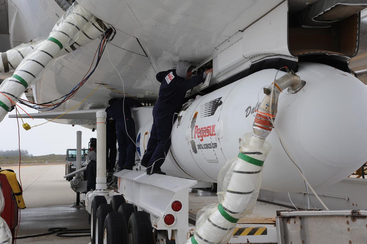VANDENBERG AIR FORCE BASE, Calif. – Technicians attach a coolant line to the fairing enclosing  NASA’s Nuclear Spectroscopic Telescope Array, or NuSTAR, mated to Orbital Sciences’ Pegasus XL rocket, beneath Orbital’s L-1011 carrier aircraft at the “hot pad,” located on the ramp adjacent to the runway on Vandenberg Air Force Base in California.      The duo will be flown from Vandenberg to the U.S. Army's Ronald Reagan Ballistic Missile Defense Test Site on Kwajalein Atoll, part of the Marshall Islands in the Pacific Ocean.  The Pegasus and its NuSTAR payload will be launched June 13 from the carrier aircraft 117 nautical miles south of Kwajalein at latitude 6.75 degrees north of the equator.  The high-energy X-ray telescope will conduct a census of black holes, map radioactive material in young supernovae remnants, and study the origins of cosmic rays and the extreme physics around collapsed stars. For more information, visit http://www.nasa.gov/nustar.  Photo credit: NASA/Chris Wiant, VAFB