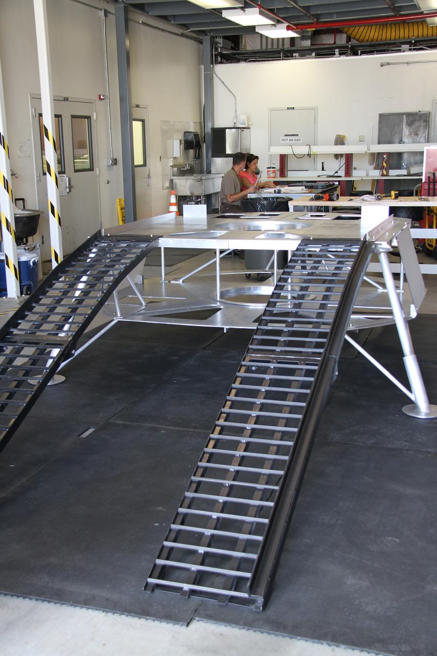 CAPE CANAVERAL, Fla. – The prototype lander for NASA’s Regolith and Environment Science and Oxygen and Lunar Volatile Extraction, or RESOLVE, project is unpacked in a test facility behind the Operations and Checkout Building at NASA’s Kennedy Space Center in Florida.  The ramps provide RESOLVE’s rover an avenue to mount or dismount the lander.     RESOLVE consists of a rover and drill provided by the Canadian Space Agency to support a NASA payload that is designed to prospect for water, ice and other lunar resources. RESOLVE also will demonstrate how future explorers can take advantage of resources at potential landing sites by manufacturing oxygen from soil. NASA will be conducting field tests in July outside of Hilo, Hawaii, with equipment and concept vehicles that demonstrate how explorers might prospect for resources and make their own oxygen for survival while on other planetary bodies.  For more information, visit http://www.nasa.gov/exploration/analogs/index.html.  Photo credit: NASA/Ben Smegelsky