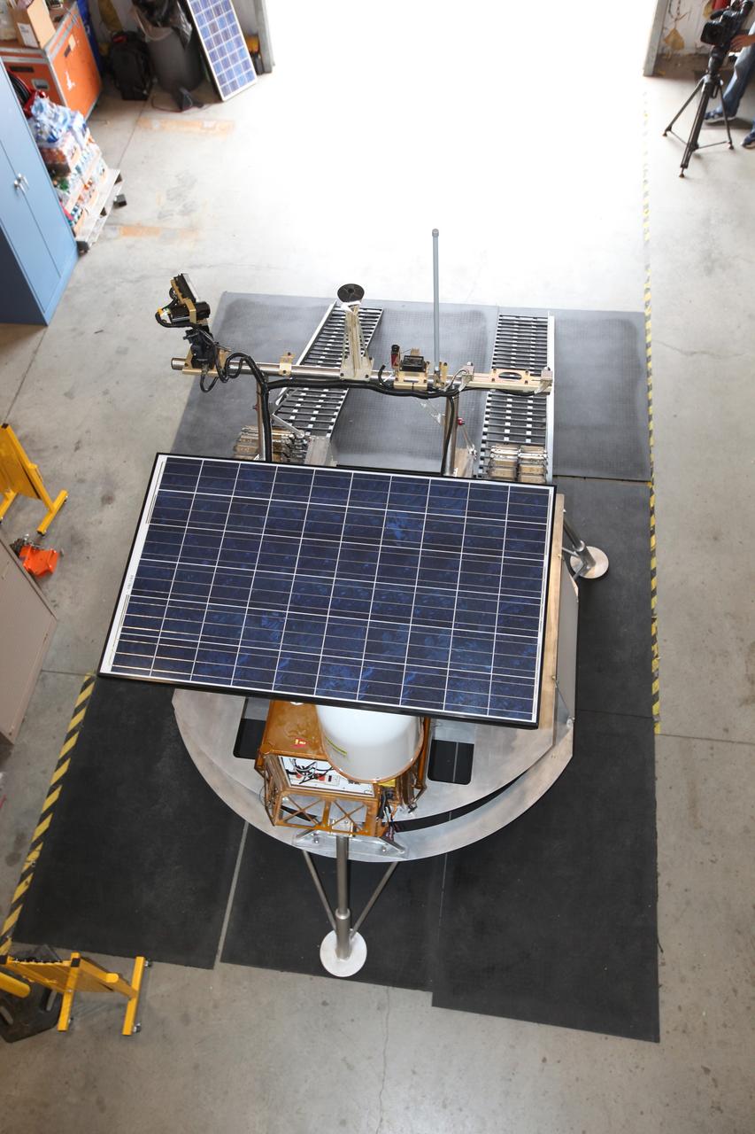 CAPE CANAVERAL, Fla. – This overhead view of the prototype rover Artemis Jr. for NASA’s Regolith and Environment Science and Oxygen and Lunar Volatile Extraction, or RESOLVE, project was taken in a test facility behind the Operations and Checkout Building at NASA’s Kennedy Space Center in Florida and provides a clear view of its solar array, as well as the placement of the ramps that provide it with an avenue to mount or dismount the prototype lander beneath it.       RESOLVE consists of a rover and drill provided by the Canadian Space Agency to support a NASA payload that is designed to prospect for water, ice and other lunar resources. RESOLVE also will demonstrate how future explorers can take advantage of resources at potential landing sites by manufacturing oxygen from soil. NASA will conduct field tests in July outside of Hilo, Hawaii, with equipment and concept vehicles that demonstrate how explorers might prospect for resources and make their own oxygen for survival while on other planetary bodies.  For more information, visit http://www.nasa.gov/exploration/analogs/index.html.  Photo credit: NASA/Dimitri Gerondidakis