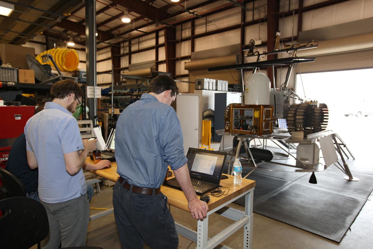 CAPE CANAVERAL, Fla. – Engineers with Neptec, a contractor to the Canadian Space Agency, prepare to conduct checkouts of the prototype rover Artemis Jr. for NASA’s Regolith and Environment Science and Oxygen and Lunar Volatile Extraction, or RESOLVE, project in a test facility behind the Operations and Checkout Building at NASA’s Kennedy Space Center in Florida.  The rover is positioned atop RESOLVE’s prototype lander.       RESOLVE consists of a rover and drill provided by the Canadian Space Agency to support a NASA payload that is designed to prospect for water, ice and other lunar resources. RESOLVE also will demonstrate how future explorers can take advantage of resources at potential landing sites by manufacturing oxygen from soil. NASA will conduct field tests in July outside of Hilo, Hawaii, with equipment and concept vehicles that demonstrate how explorers might prospect for resources and make their own oxygen for survival while on other planetary bodies.  For more information, visit http://www.nasa.gov/exploration/analogs/index.html.  Photo credit: NASA/Dimitri Gerondidakis
