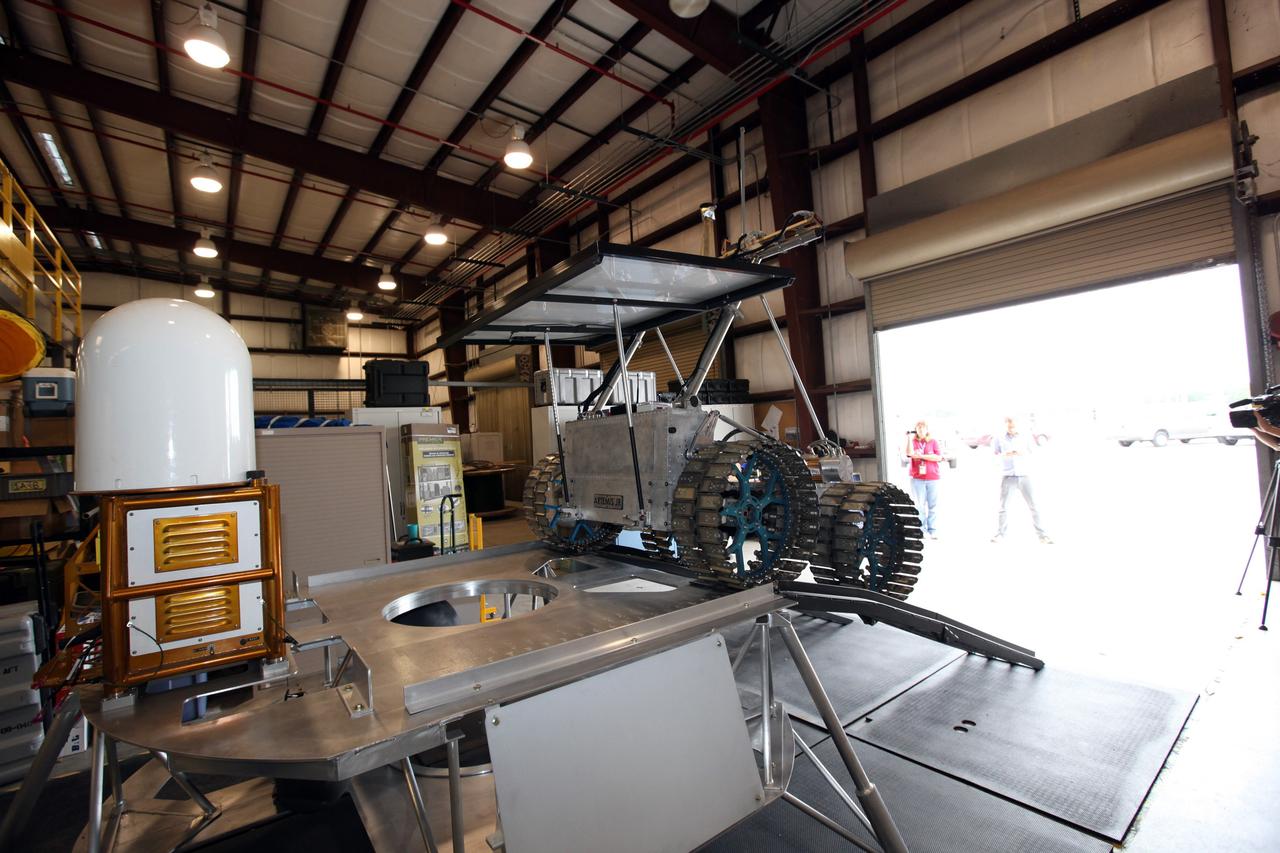 CAPE CANAVERAL, Fla. – In a test facility behind the Operations and Checkout Building at NASA’s Kennedy Space Center in Florida, the prototype rover Artemis Jr. for NASA’s Regolith and Environment Science and Oxygen and Lunar Volatile Extraction, or RESOLVE, project dismounts from the RESOLVE lander during a dry run using ramps attached to the prototype lander.      RESOLVE consists of a rover and drill provided by the Canadian Space Agency to support a NASA payload that is designed to prospect for water, ice and other lunar resources. RESOLVE also will demonstrate how future explorers can take advantage of resources at potential landing sites by manufacturing oxygen from soil. NASA will conduct field tests in July outside of Hilo, Hawaii, with equipment and concept vehicles that demonstrate how explorers might prospect for resources and make their own oxygen for survival while on other planetary bodies.  For more information, visit http://www.nasa.gov/exploration/analogs/index.html.  Photo credit: NASA/Dimitri Gerondidakis
