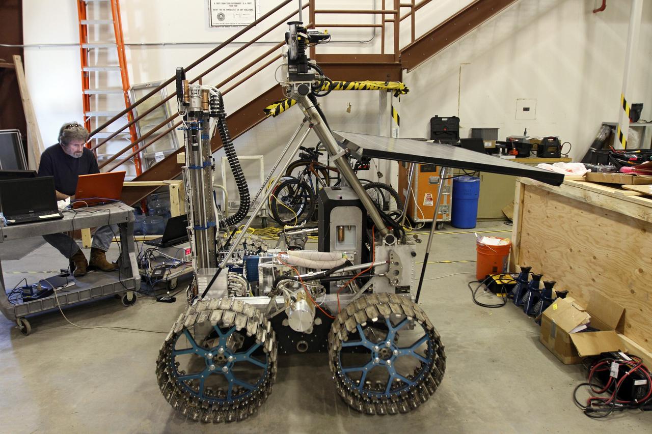 CAPE CANAVERAL, Fla. – The NASA payload is installed on the prototype rover Artemis Jr. for NASA’s Regolith and Environment Science and Oxygen and Lunar Volatile Extraction, or RESOLVE, project in a test facility behind the Operations and Checkout Building at NASA’s Kennedy Space Center in Florida. The cylindrical structure at left is the drill the tabletop surface at right is the rover’s solar array.    The drill and rover were provided to NASA by the Canadian Space Agency. The NASA payload is designed to prospect for water, ice and other lunar resources. RESOLVE also will demonstrate how future explorers can take advantage of resources at potential landing sites by manufacturing oxygen from soil. NASA will conduct field tests in July outside of Hilo, Hawaii, with equipment and concept vehicles that demonstrate how explorers might prospect for resources and make their own oxygen for survival while on other planetary bodies.  For more information, visit http://www.nasa.gov/exploration/analogs/index.html.  Photo credit: NASA/Cory Huston
