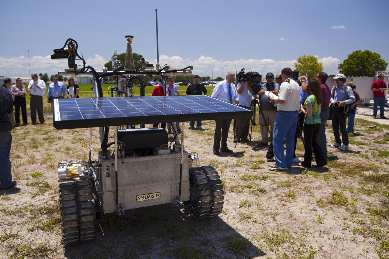 CAPE CANAVERAL, Fla. – The solar array on the prototype rover Artemis Jr. for NASA’s Regolith and Environment Science and Oxygen and Lunar Volatile Extraction, or RESOLVE, project soaks up the sunlight during a rover demonstration for media representatives in a field beside the Operations and Checkout Building at NASA’s Kennedy Space Center in Florida.     The rover and its drill are provided by the Canadian Space Agency and work in concert with NASA science instruments to prospect for water, ice and other lunar resources.  RESOLVE also will demonstrate how future explorers can take advantage of resources at potential landing sites by manufacturing oxygen from soil. NASA will conduct field tests in July outside of Hilo, Hawaii, with equipment and concept vehicles that demonstrate how explorers might prospect for resources and make their own oxygen for survival while on other planetary bodies.  For more information, visit http://www.nasa.gov/exploration/analogs/index.html.  Photo credit: NASA/Dimitri Gerondidakis