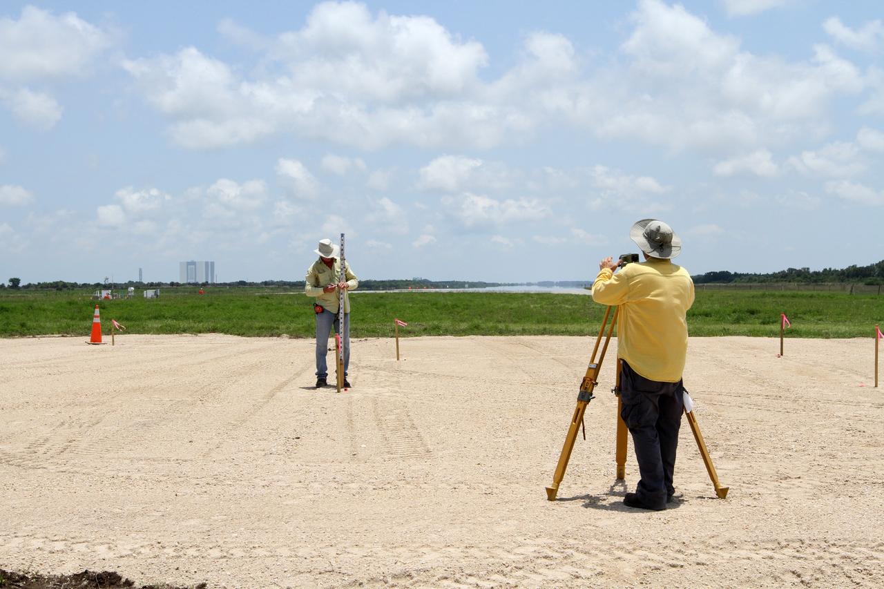 CAPE CANAVERAL, Fla. – Surveyors ensure the hazard field for the Project Morpheus lander is properly situated near the Shuttle Landing Facility at NASA’s Kennedy Space Center in Florida. In the distance is the 525-foot-tall Vehicle Assembly Building. Testing of the prototype lander has been ongoing at NASA's Johnson Space Center in Houston in preparation for its first free flight. The SLF will provide the lander with the kind of field necessary for realistic testing, complete with rocks, craters and hazards to avoid. Morpheus utilizes an autonomous landing and hazard avoidance technology, or ALHAT, payload that will allow it to navigate to clear landing sites amidst rocks, craters and other hazards during its descent. Project Morpheus is one of 20 small projects comprising the Advanced Exploration Systems, or AES, program in NASA's Human Exploration and Operations Mission Directorate. AES projects pioneer new approaches for rapidly developing prototype systems, demonstrating key capabilities and validating operational concepts for future human missions beyond Earth orbit. For more information on Project Morpheus, visit http://www.nasa.gov/centers/johnson/exploration/morpheus/index.html. Photo credit: NASA/Kim Shiflett