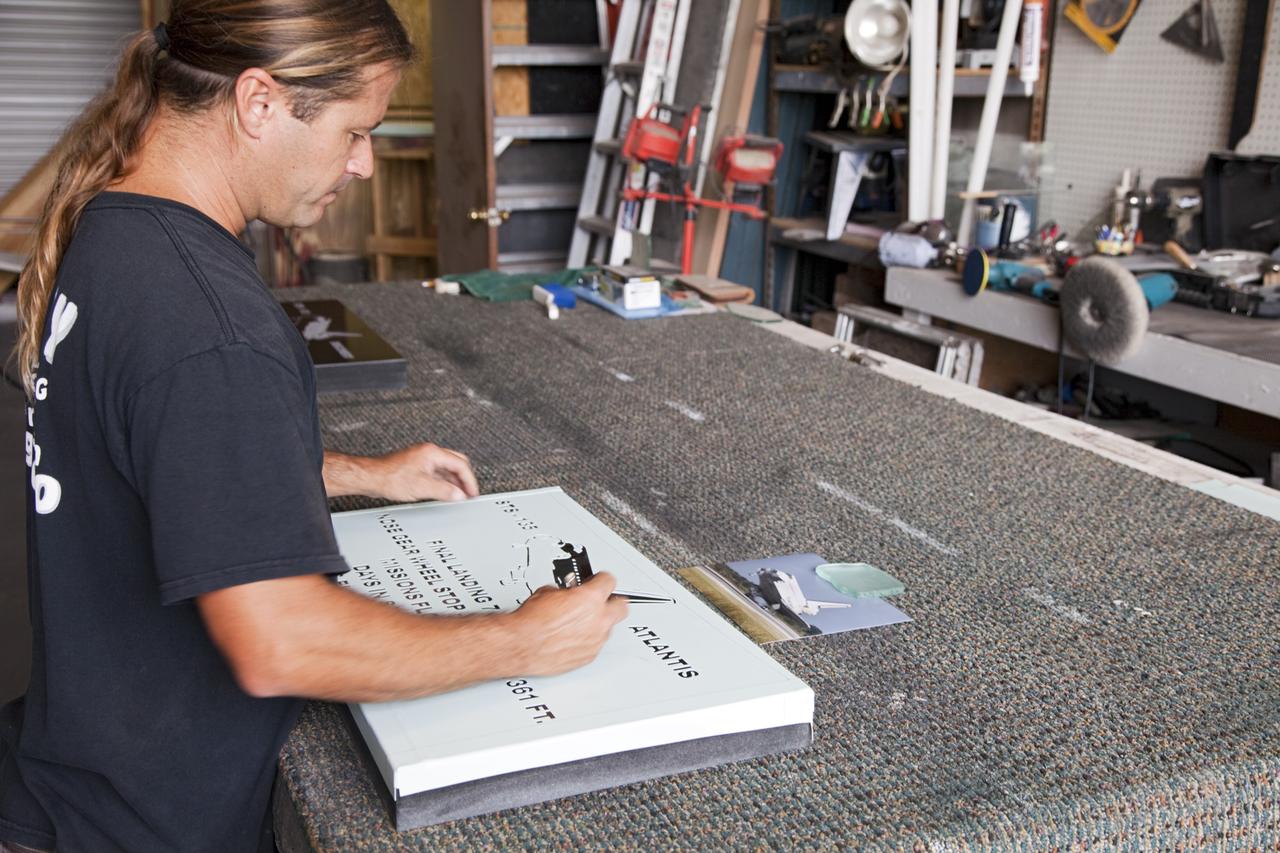 CAPE CANAVERAL, Fla. – At C Spray Glass Blasting of Cocoa Beach, Fla., a worker completes the commemorative plaque to mark space shuttle Atlantis’ wheel stop location. The special plaque will be permanently mounted at the Shuttle Landing Facility, or SLF, runway edge at NASA’s Kennedy Space Center in Florida to commemorate the final space shuttle landing. Atlantis completed the STS-135 mission by landing at the SLF on July 21, 2011, at 5:57 a.m. EDT. Atlantis flew 33 missions, completed 4,848 orbits of the Earth, traveled nearly 126 million miles and spent 307 days in space. Atlantis carried 207 astronauts to space. Photo credit: NASA/Lorne Mathre