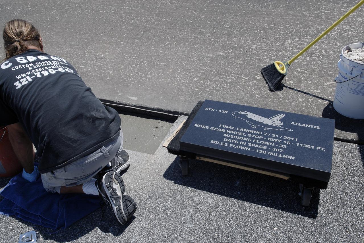 CAPE CANAVERAL, Fla. - At the Shuttle Landing Facility SLF at NASA’s Kennedy Space Center in Florida, Chad Stout with C Spray Glass Blasting in Cocoa, Fla., prepares to install a special plaque to mark the nose gear wheel stop of space shuttle Atlantis. The black granite plaque, which is 16 by 28 inches, is the third plaque permanently mounted to commemorate the final landing of each of the three orbiters. Atlantis completed the STS-135 mission by landing at the SLF on July 21, 2011, at 5:57 a.m. Atlantis flew 33 missions, completed 4,848 orbits of the Earth, traveled nearly 126 million miles and spent 307 days in space. Atlantis carried 207 astronauts to space. Photo credit: NASA/Charisse Nahser
