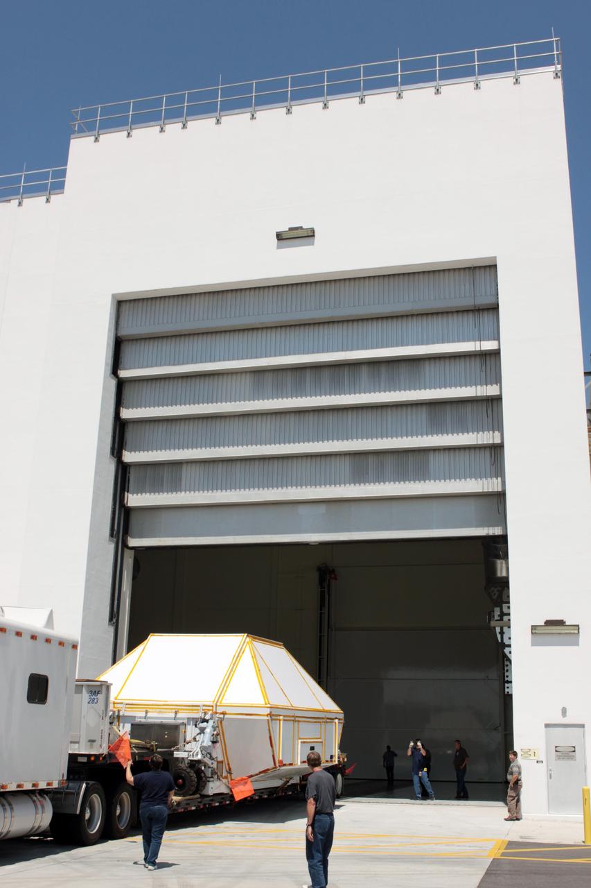 CAPE CANAVERAL, Fla. - Secured inside a transportation container, the Orion crew module is moved through the open high-bay door to the Operations and Checkout Building at NASA's Kennedy Space Center in Florida.      Slated for Exploration Flight Test-1, an uncrewed mission planned for 2014, the capsule will travel farther into space than any human spacecraft has gone in more than 40 years. NASA's Michoud Assembly Facility in New Orleans built the crew module pressure vessel. The Orion production team will prepare the module for flight by installing heat-shielding thermal protection systems, avionics and other subsystems. For more information, visit http://www.nasa.gov/orion. Photo credit: NASA/Jim Grossmann