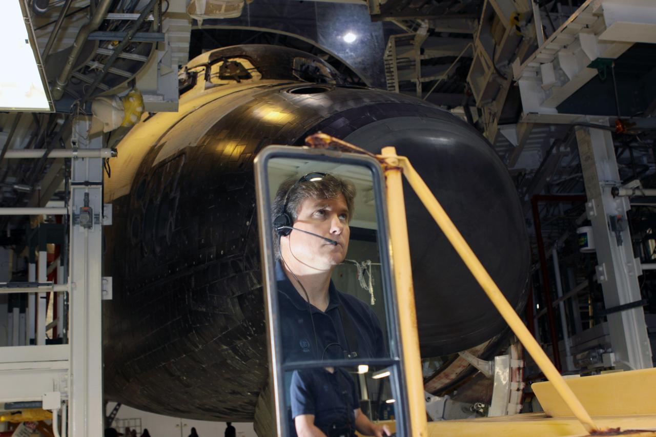 CAPE CANAVERAL, Fla. - A technician is reflected in the mirror of a transporter as preparations begin to move space shuttle Atlantis out of Orbiter Processing Facility-1 and into High Bay 4 of the nearby Vehicle Assembly Building at NASA's Kennedy Space Center in Florida.      The work is part of the Space Shuttle Program's transition and retirement processing of the space shuttle fleet. A groundbreaking was held Jan. 18 for Atlantis' future home, a 65,000-square-foot exhibit hall in Shuttle Plaza at the Kennedy Space Center Visitor Complex. Atlantis is scheduled to roll over to the visitor complex in November in preparation for the exhibit's grand opening in July 2013. Photo credit: NASA/Jim Grossmann