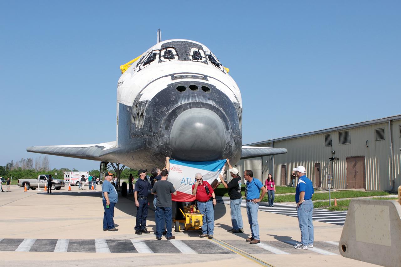 CAPE CANAVERAL, Fla. - Space shuttle technicians display an Atlantis flag on the spacecraft as it is moved from Orbiter Processing Facility Bay 1 into High Bay 4 of the nearby Vehicle Assembly Building at NASA's Kennedy Space Center in Florida.    The work is part of the Space Shuttle Program's transition and retirement processing of the space shuttle fleet. A groundbreaking was held Jan. 18 for Atlantis' future home, a 65,000-square-foot exhibit hall in Shuttle Plaza at the Kennedy Space Center Visitor Complex. Atlantis is scheduled to roll over to the visitor complex in November in preparation for the exhibit's grand opening in July 2013. For more information, visit http://www.nasa.gov/transition. Photo credit: NASA/Jim Grossmann