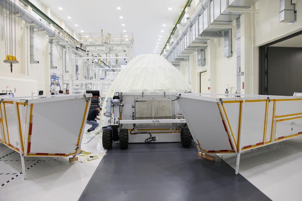 CAPE CANAVERAL, Fla. - Wrapped in a protective cover, the Orion crew module is removed from its transportation container inside the Operations and Checkout Building high bay at NASA's Kennedy Space Center in Florida.    Slated for Exploration Flight Test-1, an uncrewed mission planned for 2014, the capsule will travel farther into space than any human spacecraft has gone in more than 40 years. NASA's Michoud Assembly Facility in New Orleans built the crew module pressure vessel. The Orion production team will prepare the module for flight by installing heat-shielding thermal protection systems, avionics and other subsystems. For more information, visit http://www.nasa.gov/orion.  Photo credit: NASA/Gianni Woods