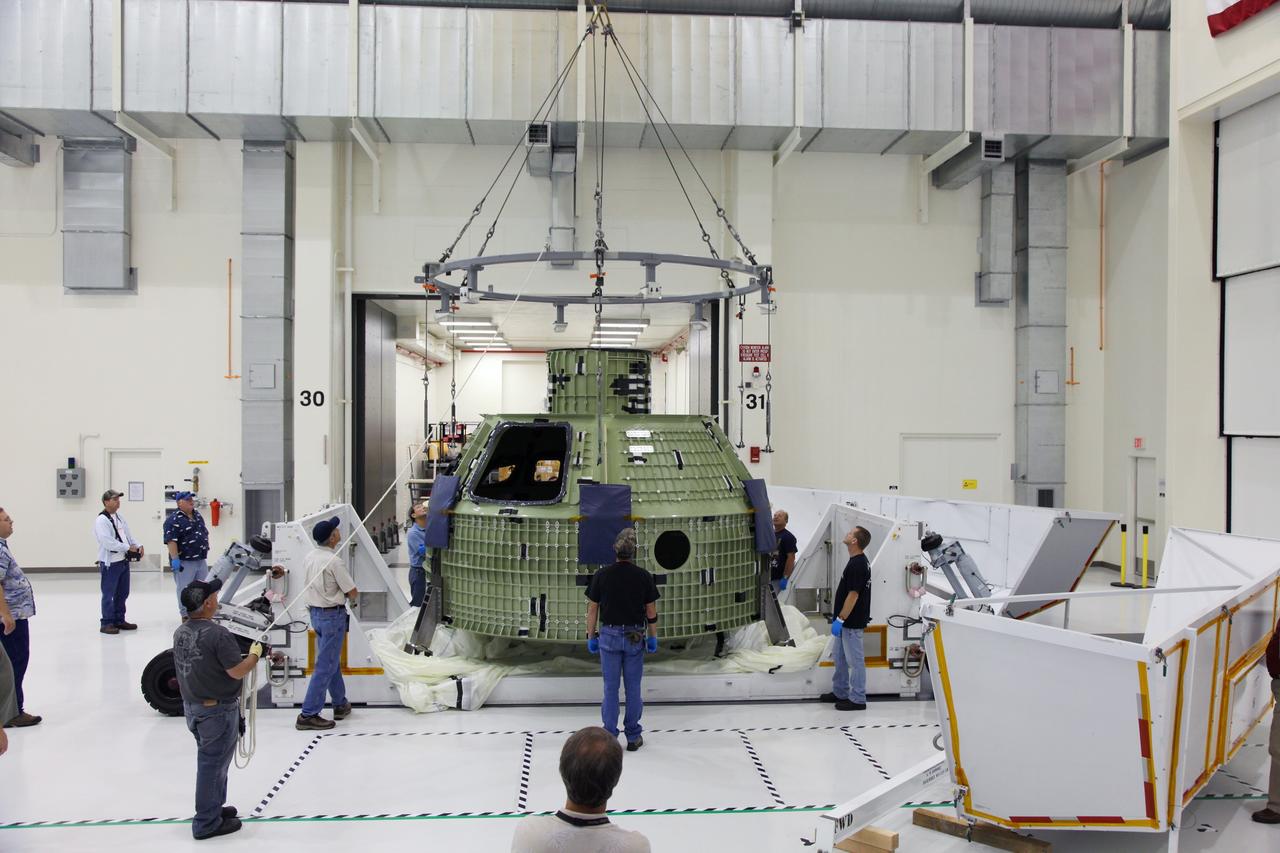 CAPE CANAVERAL, Fla. - Technicians use a crane to position the Orion crew module on a workstand in the Operations and Checkout Building high bay at NASA's Kennedy Space Center in Florida.    Slated for Exploration Flight Test-1, an uncrewed mission planned for 2014, the capsule will travel farther into space than any human spacecraft has gone in more than 40 years. NASA's Michoud Assembly Facility in New Orleans built the crew module pressure vessel. The Orion production team will prepare the module for flight by installing heat-shielding thermal protection systems, avionics and other subsystems. For more information, visit http://www.nasa.gov/orion.  Photo credit: NASA/Gianni Woods