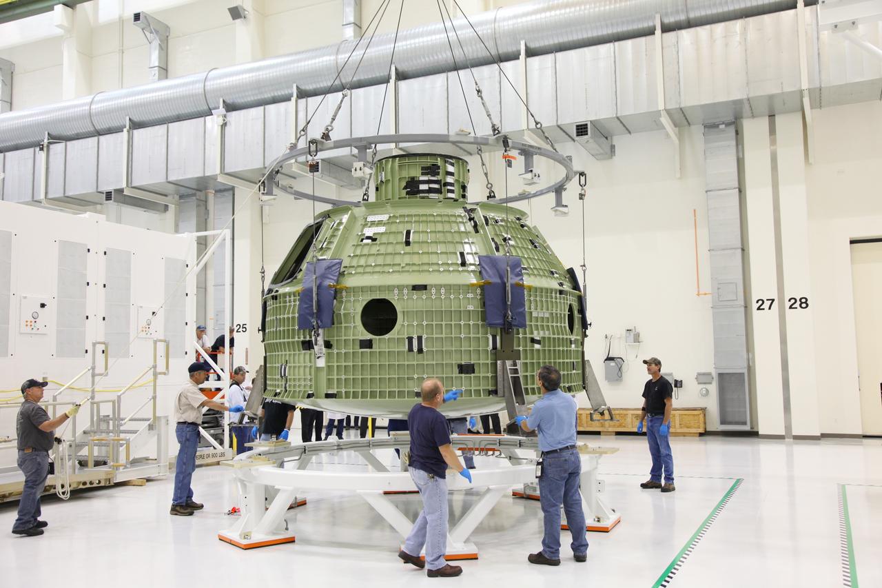 CAPE CANAVERAL, Fla. - Technicians use a crane to position the Orion crew module on a workstand in the Operations and Checkout Building high bay at NASA's Kennedy Space Center in Florida.    Slated for Exploration Flight Test-1, an uncrewed mission planned for 2014, the capsule will travel farther into space than any human spacecraft has gone in more than 40 years. NASA's Michoud Assembly Facility in New Orleans built the crew module pressure vessel. The Orion production team will prepare the module for flight by installing heat-shielding thermal protection systems, avionics and other subsystems. For more information, visit http://www.nasa.gov/orion.  Photo credit: NASA/Gianni Woods