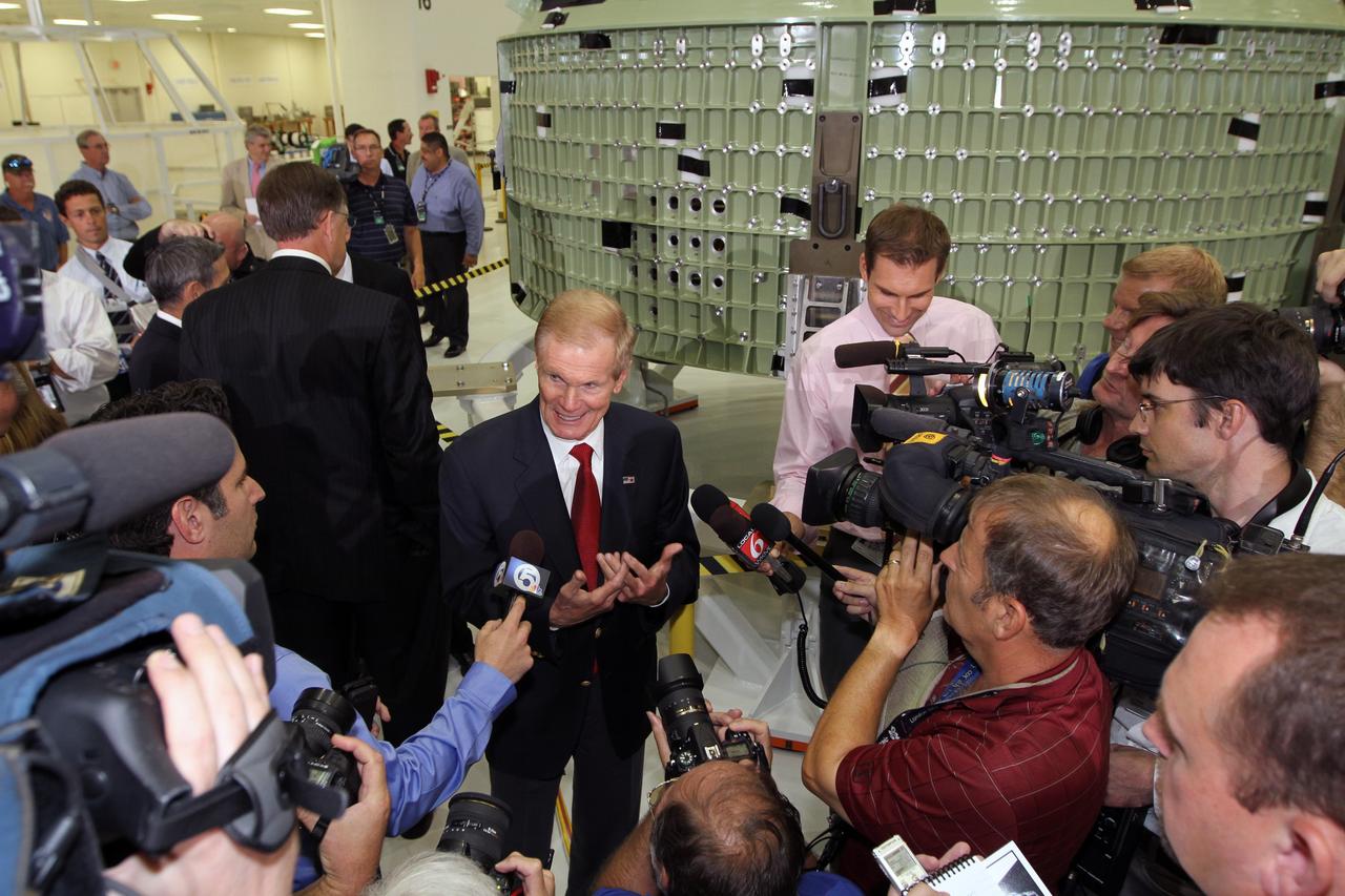 CAPE CANAVERAL, Fla. – U.S. Senator Bill Nelson, center, talks to the media in Kennedy Space Center's Operations and Checkout Building high bay following an event marking the arrival in Florida of NASA's first space-bound Orion capsule, behind him.    Slated for Exploration Flight Test-1, an uncrewed mission planned for 2014, the capsule will travel farther into space than any human spacecraft has gone in more than 40 years. The capsule was shipped to Kennedy from NASA's Michoud Assembly Facility in New Orleans where the crew module pressure vessel was built. The Orion production team will prepare the module for flight at Kennedy by installing heat-shielding thermal protection systems, avionics and other subsystems. For more information, visit http://www.nasa.gov/orion.  Photo credit: NASA/Kim Shiflett