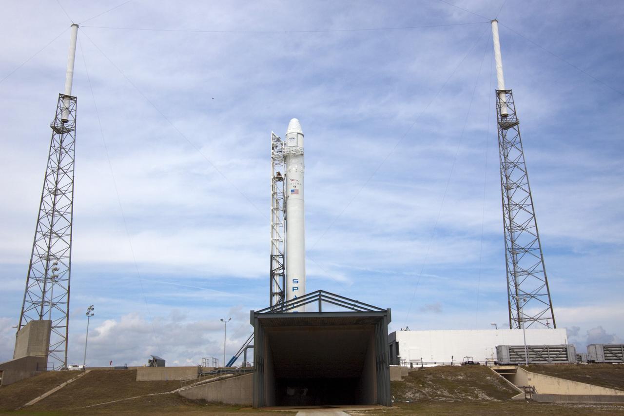 CAPE CANAVERAL, Fla. – Partially hidden behind a flame and exhaust deflector, the SpaceX Falcon 9 rocket stands at Space Launch Complex-40 on Cape Canaveral Air Force Station in Florida. Liftoff with the SpaceX Dragon capsule aboard is set for 4:55 a.m. EDT on May 19. The launch will be the company's second demonstration test flight for NASA's Commercial Orbital Transportation Services Program, or COTS.    During the flight, the capsule will conduct a series of check-out procedures to test and prove its systems, including rendezvous and berthing with the International Space Station. If the capsule performs as planned, the cargo and experiments it is carrying will be transferred to the station. The cargo includes food, water and provisions for the station’s Expedition crews, such as clothing, batteries and computer equipment. Under COTS, NASA has partnered with two aerospace companies to deliver cargo to the station. For more information, visit http://www.nasa.gov/spacex Photo credit: NASA/Jim Grossmann