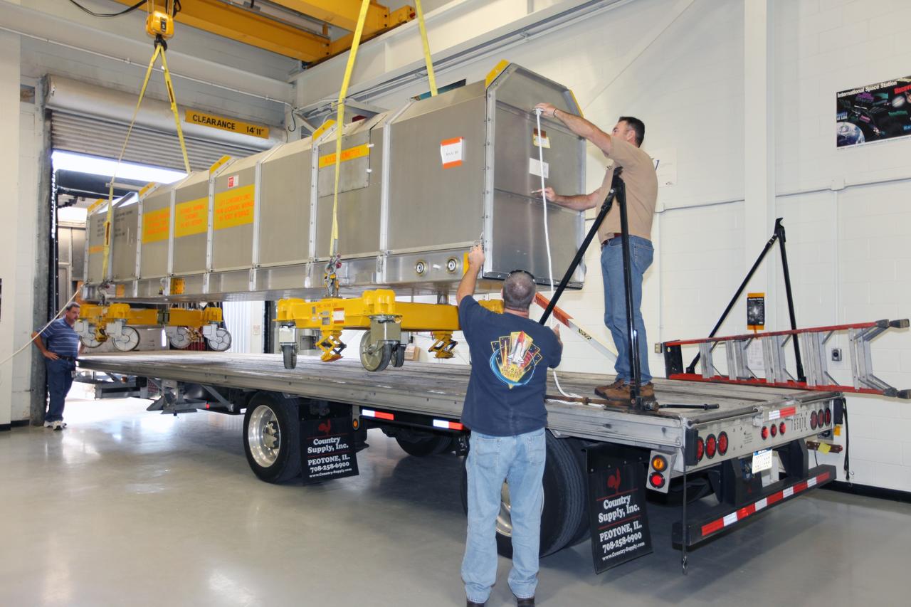 CAPE CANAVERAL, Fla. - Inside the Vehicle Assembly Building at NASA’s Kennedy Space Center in Florida, United Space Alliance workers help guide the container holding the remote manipulator system, or RMS, onto a flatbed truck for shipment back to the Canadian Space Agency. The RMS, also called the Canadarm, was manufactured for NASA’s Space Shuttle Program by SPAR Aerospace Ltd., which later became a part of MD Robotics in Ontario, Canada. During shuttle missions, the RMS was attached in the payload bay. Mission specialists operated the arm to remove payloads from the payload bay and hand them off to the larger Canadarm 2 on the International Space Station. The shuttle arm also was used during astronaut spacewalks. Photo credit: NASA/Kim Shiflett