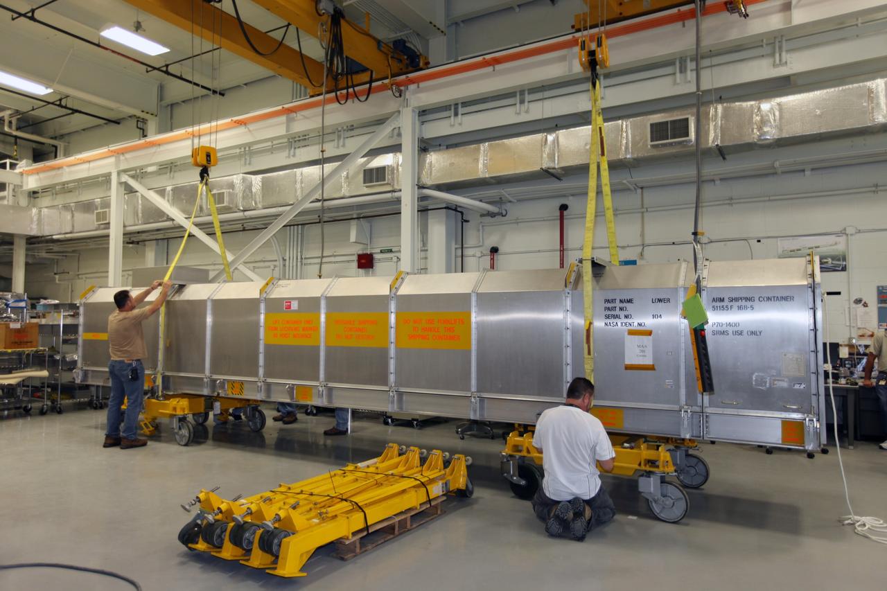 CAPE CANAVERAL, Fla. - Inside the Vehicle Assembly Building at NASA’s Kennedy Space Center in Florida, United Space Alliance workers attach lifting cranes to the container holding the remote manipulator system, or RMS. The RMS is placed on a flatbed truck for shipment back to the Canadian Space Agency. The RMS, also called the Canadarm, was manufactured for NASA’s Space Shuttle Program by SPAR Aerospace Ltd., which later became a part of MD Robotics in Ontario, Canada. During shuttle missions, the RMS was attached in the payload bay. Mission specialists operated the arm to remove payloads from the payload bay and hand them off to the larger Canadarm 2 on the International Space Station. The shuttle arm also was used during astronaut spacewalks. Photo credit: NASA/Kim Shiflett