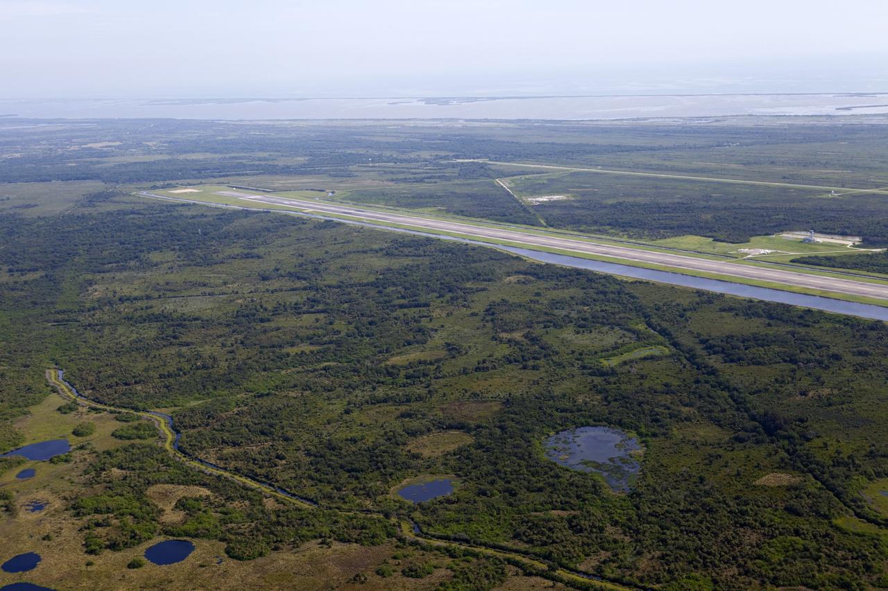 CAPE CANAVERAL, Fla. – This aerial view shows the north end of the Kennedy Space Center’s 15,000-foot long Shuttle Landing Facility. On the far left at the end of the runway, a rock and crater-filled planetary scape has been built so engineers can test the Autonomous Landing and Hazard Avoidance Technology, or ALHAT system on the Project Morpheus lander. Testing will demonstrate ALHAT’s ability to provide required navigation data negotiating the Morpheus lander away from risks during descent. Checkout of the prototype lander has been ongoing at NASA’s Johnson Space Center in Houston in preparation for its first free flight. The SLF site will provide the lander with the kind of field necessary for realistic testing. Project Morpheus is one of 20 small projects comprising the Advanced Exploration Systems, or AES, program in NASA’s Human Exploration and Operations Mission Directorate. AES projects pioneer new approaches for rapidly developing prototype systems, demonstrating key capabilities and validating operational concepts for future human missions beyond Earth orbit. For more information on Project Morpheus, visit http://www.nasa.gov/centers/johnson/exploration/morpheus/index.html Photo credit: NASA/Kim Shiflett