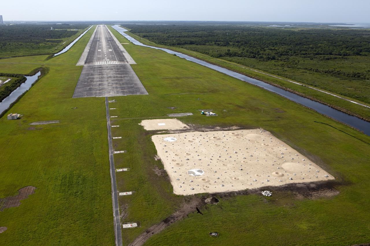 CAPE CANAVERAL, Fla. – This aerial view shows the north end of the Kennedy Space Center’s Shuttle Landing Facility. At the end of the runway is a rock and crater-filled planetary scape has been built so engineers can test the Autonomous Landing and Hazard Avoidance Technology, or ALHAT system on the Project Morpheus lander. Testing will demonstrate ALHAT’s ability to provide required navigation data negotiating the Morpheus lander away from risks during descent. Checkout of the prototype lander has been ongoing at NASA’s Johnson Space Center in Houston in preparation for its first free flight. The SLF site will provide the lander with the kind of field necessary for realistic testing. Project Morpheus is one of 20 small projects comprising the Advanced Exploration Systems, or AES, program in NASA’s Human Exploration and Operations Mission Directorate. AES projects pioneer new approaches for rapidly developing prototype systems, demonstrating key capabilities and validating operational concepts for future human missions beyond Earth orbit. For more information on Project Morpheus, visit http://www.nasa.gov/centers/johnson/exploration/morpheus/index.html Photo credit: NASA/Kim Shiflett
