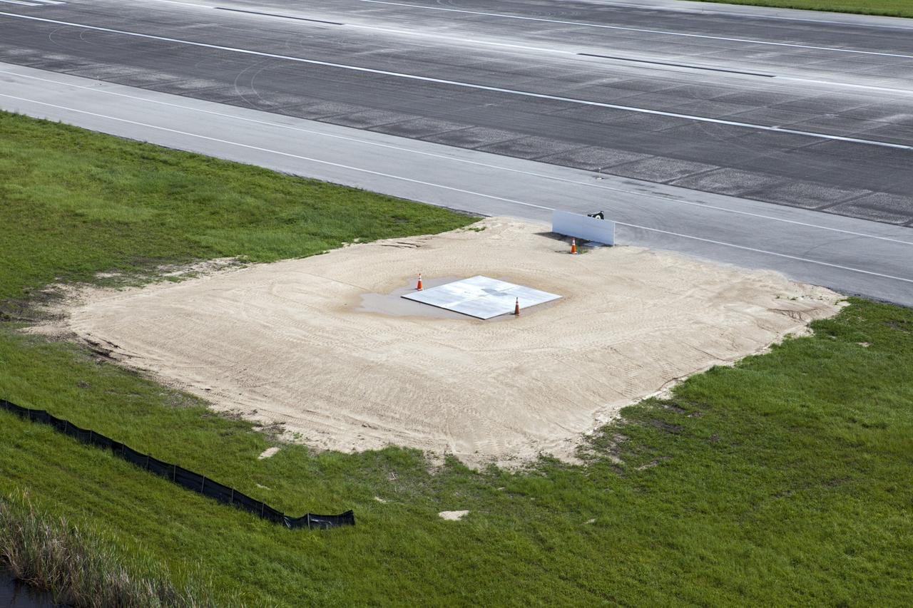 CAPE CANAVERAL, Fla. – This aerial view shows the launch platform for the Project Morpheus lander at the midfield point of the Shuttle Landing Facility, or SLF, at NASA’s Kennedy Space Center in Florida. At the north end of the runway is a rock and crater-filled planetary scape built so engineers can test the Autonomous Landing and Hazard Avoidance Technology, or ALHAT system on the Morpheus lander. Testing will demonstrate ALHAT’s ability to provide required navigation data negotiating the Morpheus lander away from risks during descent.      Checkout of the prototype lander has been ongoing at NASA’s Johnson Space Center in Houston in preparation for its first free flight. The SLF site will provide the lander with the kind of field necessary for realistic testing. Project Morpheus is one of 20 small projects comprising the Advanced Exploration Systems, or AES, program in NASA’s Human Exploration and Operations Mission Directorate. AES projects pioneer new approaches for rapidly developing prototype systems, demonstrating key capabilities and validating operational concepts for future human missions beyond Earth orbit. For more information on Project Morpheus, visit http://www.nasa.gov/centers/johnson/exploration/morpheus/index.html  Photo credit: NASA/Kim Shiflett